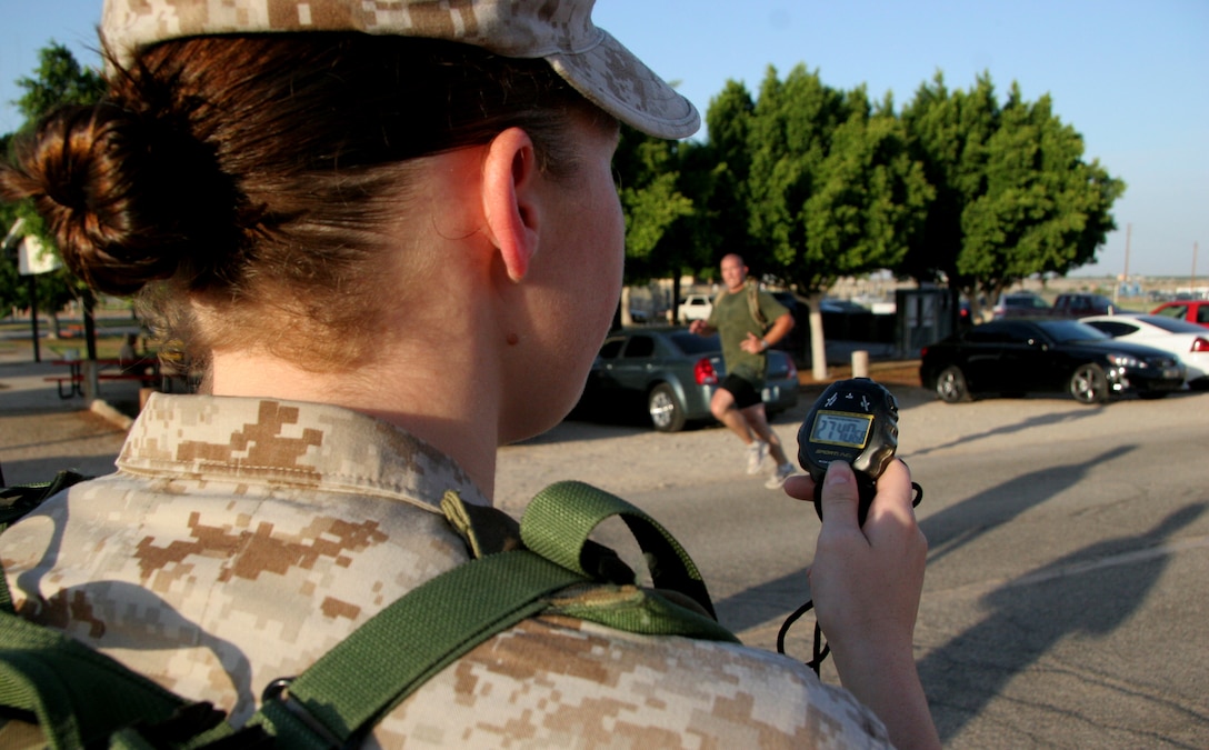 Petty Officer 3rd Class Lauren Scharr, station corpsman, reads off a stopwatch as a Headquarters and Headquarters Squadron Marine crosses the physical fitness test course finish line at the Marine Corps Air Station in Yuma, Ariz., June 30, 2009. Active duty Marines are required to run two PFTs annually, one before June 30 and one before Dec. 31.