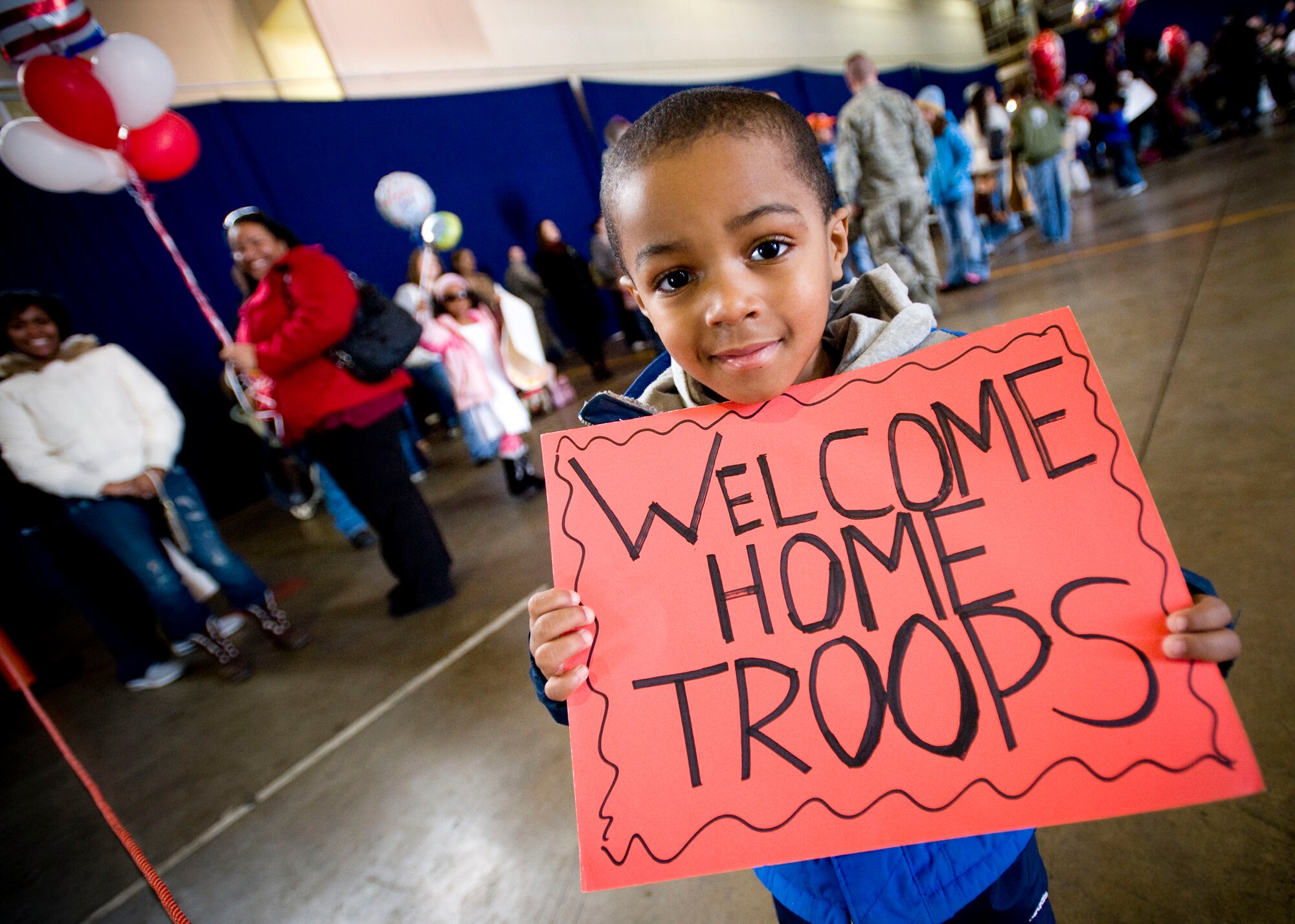 MISAWA AIR BASE, Japan -- John Parker Jr., 4, proudly displays a sign celebrating his father's return March 1, 2009. John waited with countless other friends and family members waiting for the passenger airplane bringing friends and families home. John and his family are from Houston, Texas. (U.S. Air Force photo by Staff Sgt. Samuel Morse)