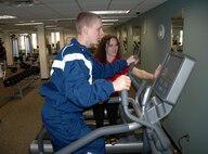 April Crooks, fitness center manager, demonstrates features of one of the facility's five new elliptical trainers for Trey Brock, a 919th Special Operations Wing student hire.  The trainer is one of more than a dozen new  machines the wing added to help its members expand their workout options and achieve their personal fitness goals.  (U.S. Air Force photo/Dan Neely)  