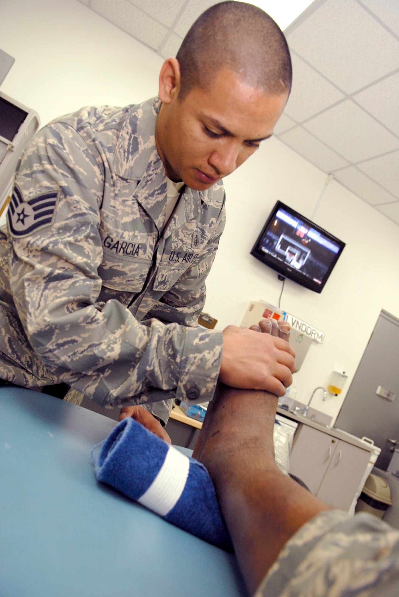 Staff Sgt. David Garcia, the 379th Expeditionary Medical Group NCOIC of the physical therapy clinic at an air base in Southwest Asia, performs isometric muscle strengthening Feb. 19 on a patient who sprained his ankle.  The physical therapists concentrate on injuries involving ankles, knees, hips, back and neck and work to get warfighters back on the job as soon as safely possible.  They also travel around the base talking to individuals and groups about ways to prevent injuries.  Sergeant Garcia is deployed from Andrews Air Force Base, Md.  (U.S. Air Force photo/Airman 1st Class Andrew Satran)
