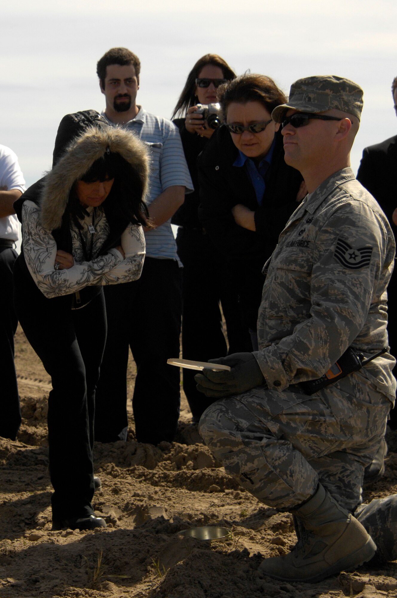 VANDENBERG AIR FORCE BASE, Calif. -- Transportation Security Administration members peer into a buried coffee can holding a blasting cap as Tech. Sgt. Robert Brown, 30th Engineer Squadron explosive ordnance technician stands by for safety during an explosive ordnance awareness course Feb. 27 here. (U.S. Air Force photo/Senior Airman Matthew Plew)