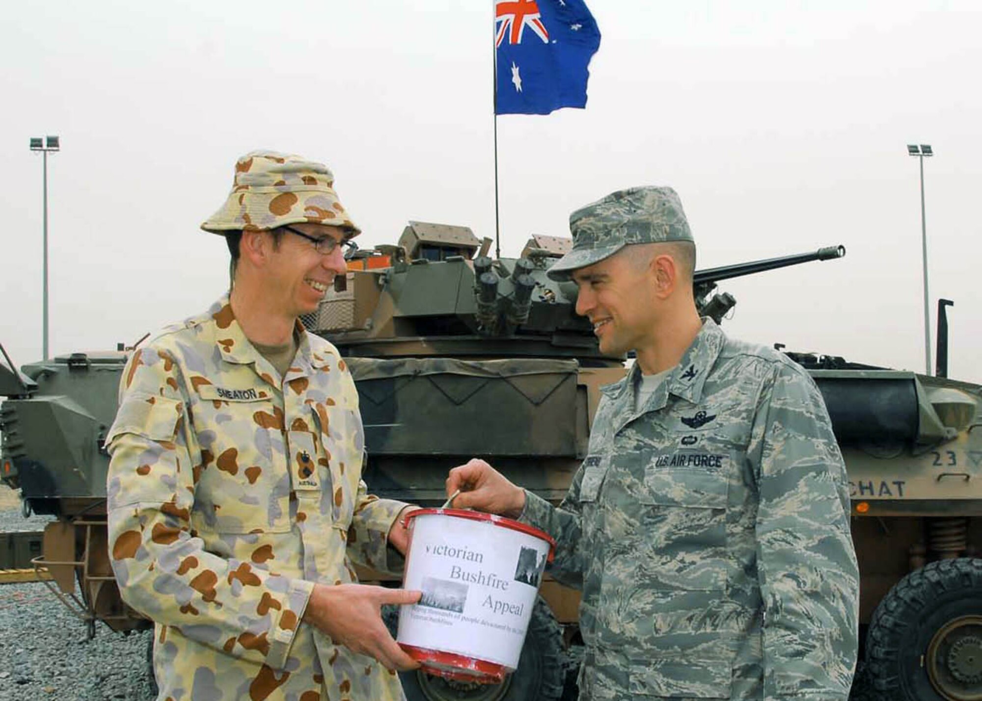 Col. Cameron Torrens, 386th Air Expeditionary Wing commander, donates money Feb. 27 on behalf of the wing to Australian Army Lt. Col. Ed Smeaton, Force Support Unit 1 commander, at an air base in Southwest Asia. The money will be given to assist the victims of brush fires in Australia that killed more than 200 Australians and left hundreds more homeless (U.S. Air Force photo/Senior Airman Courtney Richardson)