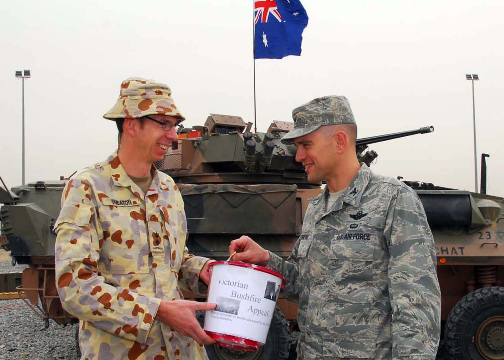 SOUTHWEST ASIA -- Col. Cameron Torrens donates money on behalf of the 386th Air Expeditionary Wing to Australian Army Lt. Col. Ed Smeaton, Force Support Unit 1 commander, at an air base in Southwest Asia, Feb. 27. The money will be given to the Bushfire Appeal set up by Commonwealth Bank. (U.S. Air Force photo/ Senior Airman Courtney Richardson)