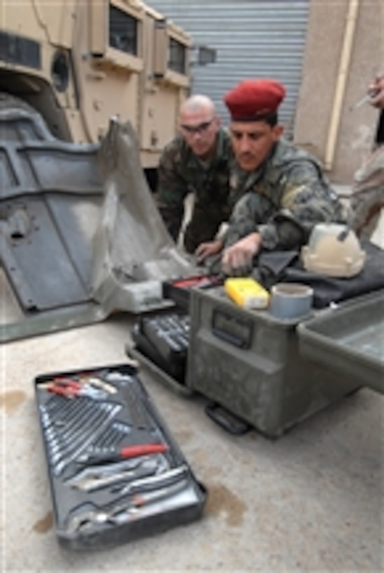 U.S. Army Sgt. Raymond Averesch (left) from the Military Transition and Training Team trains an Iraqi soldier with the 6th Iraqi Division to change out headlight assemblies on a Humvee in Kadhimiya, Iraq, on Feb. 23, 2009.  