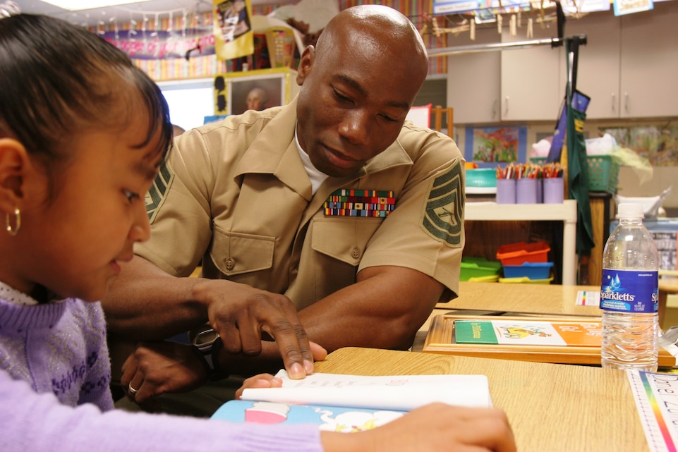 Gunnery Sgt. Collin C. Bennett, staff noncommissioned officer for the flightline, Marine Medium Helicopter Training Squadron 164, Marine Aircraft Group 39, 3rd Marine Air Wing, reads to Edith Osio, second-grade student, at Vista’s Academy of Visual and Performing Arts Monday in celebration of Read Across America and the late Dr. Seuss’ 105th birthday.::r::::n::