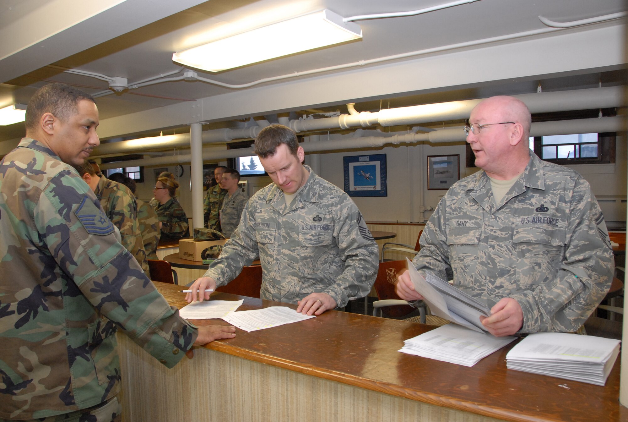ELMENDORF AIR FORCE BASE, Alaska -- Senior Master Sgt.'s Scott Anderson and Rich Gary, 477th Force Support Squadron, perform final outprocessing procedures for Master Sgt. Todd McGee, 477th Civil Engineer Squadron.  Sgt. McGee is deploying to Iraq in the upcoming weeks.  This is the first deployment for the 477 CES since World War II.  They are the only Air Force Reserve Civil Engineer Squadron in Alaska and are assigned to the 477th Fighter Group. (US Air Force Photo by Staff Sgt. Rhiannon Willard)