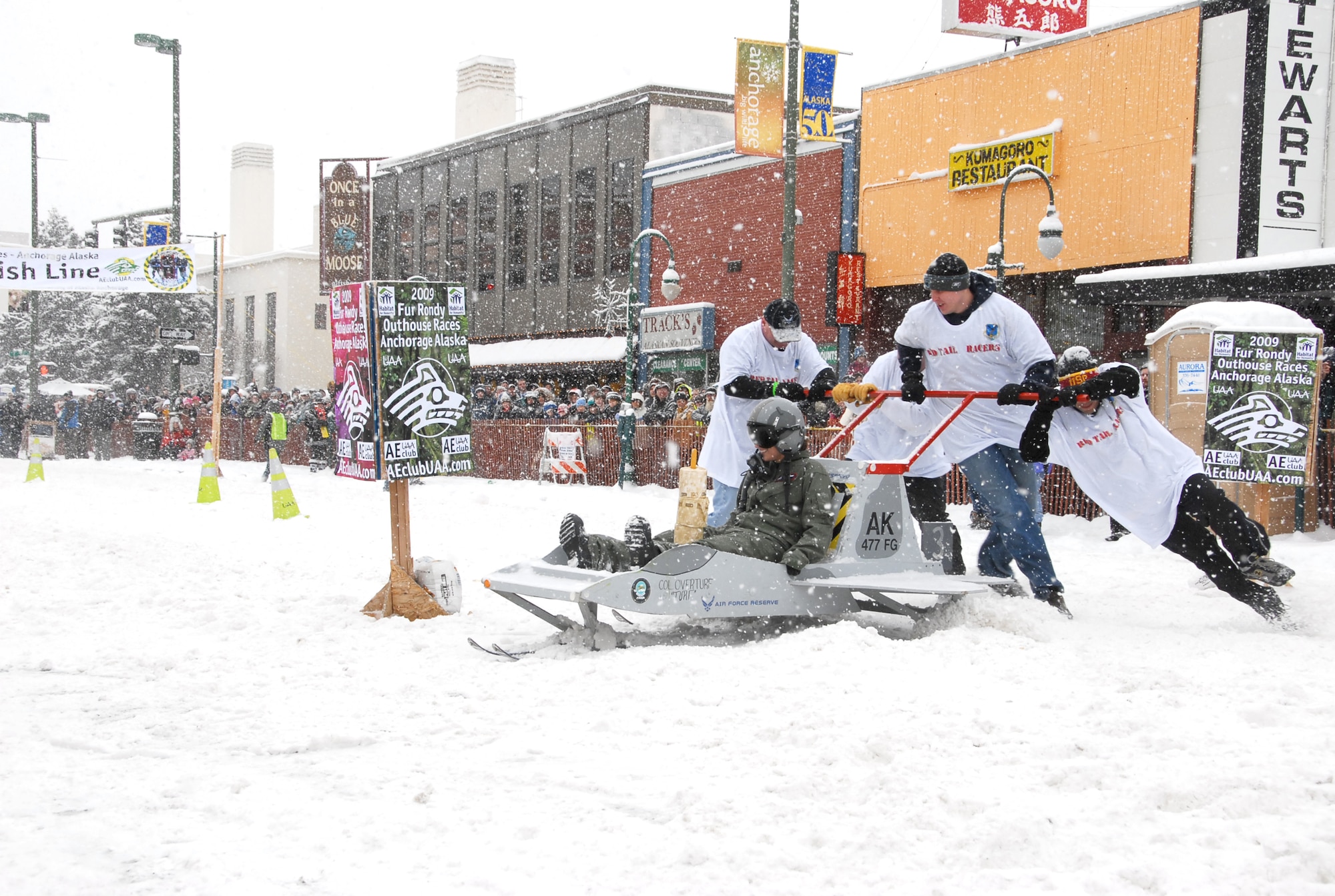 ANCHORAGE, Alaska -- Members of the 477th Fighter Group push Staff Sgt. Holly Carroll, 477th Aircraft Maintenance Squadron, during "Outhouse Race" in the Anchorage, Alaska Fur Rondy celebration on February 28. Although the "Raptor Crapper" did not place amongst the winners, it was given the "Cleanest Outhouse" award.  (US Air Force Photo by Staff Sgt. Rhiannon Willard)