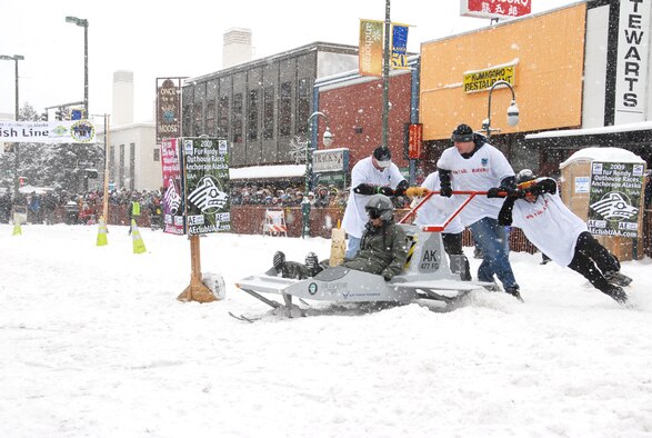 ANCHORAGE, Alaska -- Members of the 477th Fighter Group push Staff Sgt. Holly Carroll, 477th Aircraft Maintenance Squadron, during "Outhouse Race" in the Anchorage, Alaska Fur Rondy celebration on February 28. Although the "Raptor Crapper" did not place amongst the winners, it was given the "Cleanest Outhouse" award.  (US Air Force Photo by Staff Sgt. Rhiannon Willard)