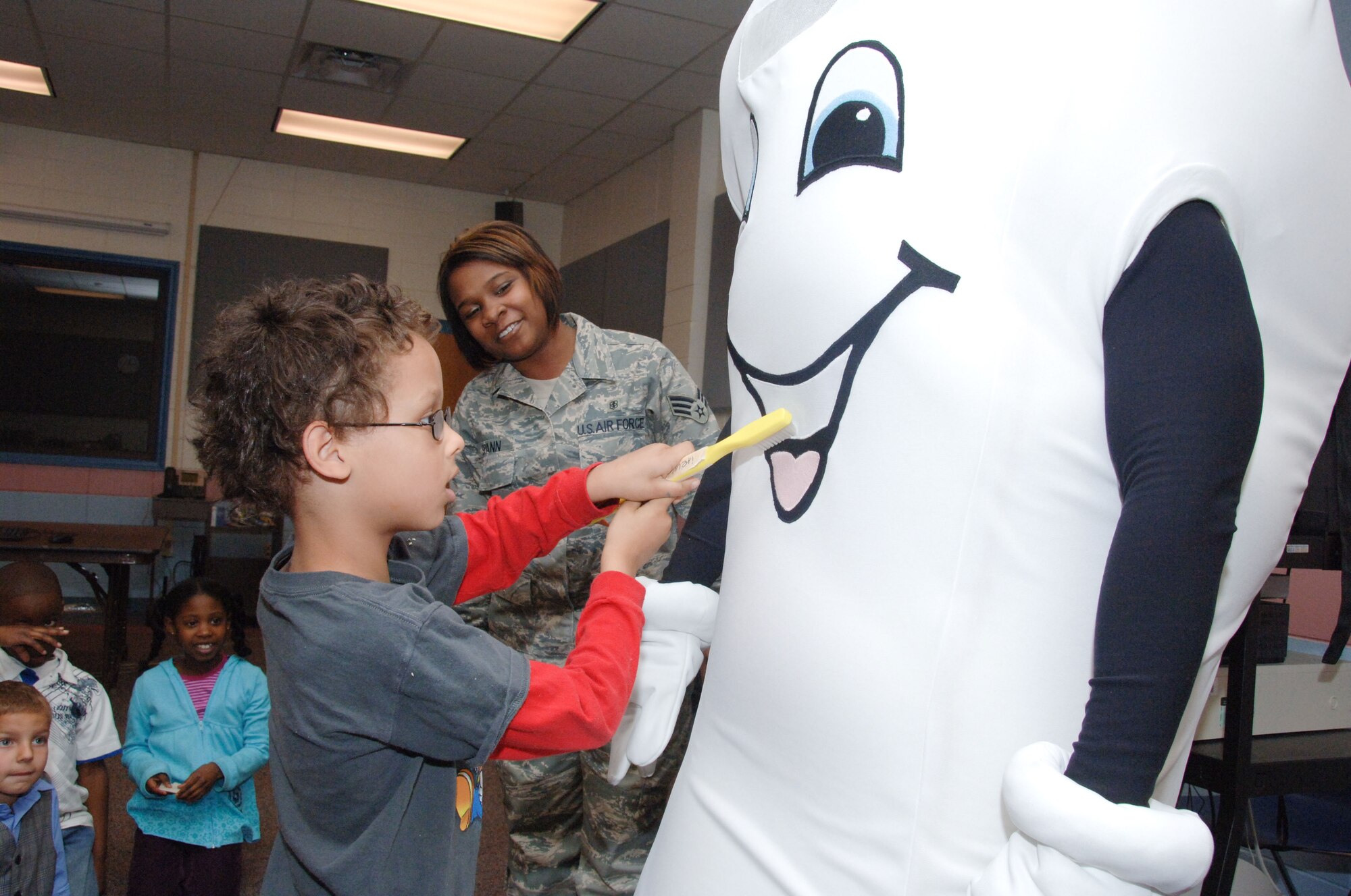 "Major Molar" and members of the Maxwell Dental Clinic paid a visit to Maxwell Elementary School on Feb. 24 as February's National Children's Dental Health Month came to a close. With the help of Major Molar, Jordan Glenn learns the correct way to brush as Senior Airman Jasmine Spann, a dental assistant at the clinic, observes.  Dental Clinic members visited the school over two days to talk about oral health care and distribute activity booklets. (Air Force photo by Melanie Rodgers Cox)