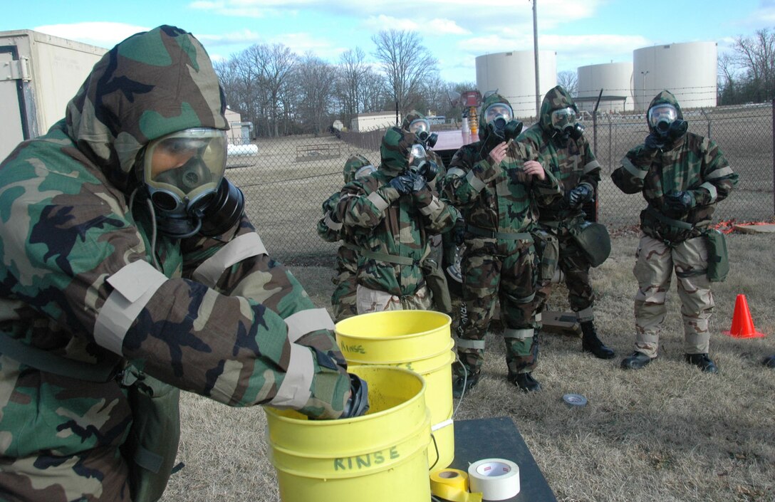 A group of 89th Airlift Wing personnel, wearing Mission Oriented Protective Posture gear, file through a decontamination station, consisting of bleach and water, Feb. 20, in preparation for an upcoming Operational Readiness Inspection held at Travis AFB, Fairfield, Ca. Read the Capital Flyer March 6 for a full pictorial on the 89 AW preparations for the inspection. (US Air Force photo by Bobby Jones)