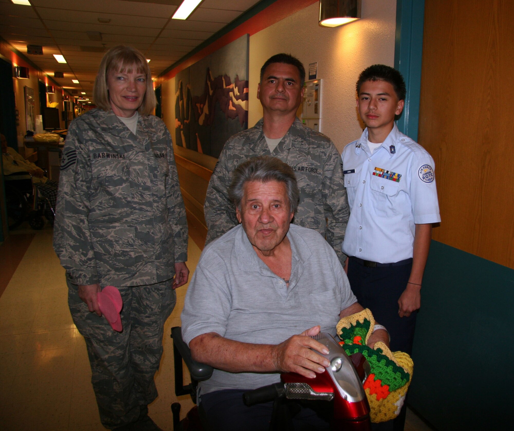 TUCSON, Ariz. -- Air Force Reserve Tech. Sgt. Beth Barwinski and Tech. Sgt. Augustin Luera and his son Estevan pose for a photo with Mr. Moses Gnavarrette, U.S. Air Force veteran, after talking to him about his days spent in the Air Force Feb. 11, 2009 at the Southern Arizona VA Health Care System, Tucson, Ariz. during the National Salute to Hospitalized Veterans Celebration.  Reservists and family members gave the veterans valentines, made by local school children, and blankets, made by VA volunteers, to hospitalized veterans.  During their visit they shared "war stories' from the past and present" giving the precious gift of time. The National Salute to Hospitalized Veterans is a celebration conducted around Valentines Day every year to pay tribute and express appreciation to hospitalized veterans.  This event is also intended to increase community awareness of the role of the medical center and encourage individuals to visit hospitalized veterans and become involved as volunteers. (U.S. Air Force photo/Master Sgt. Ruby Zarzyczny)