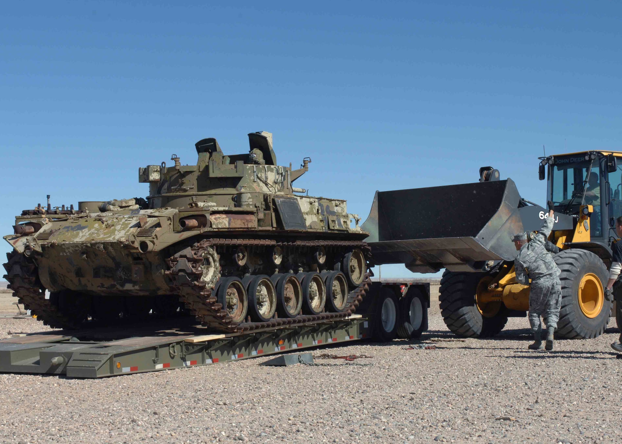 CANNON AIR FORCE BASE, N.M. -- George Tidwell, Melrose Air Force Range heavy equipment operator, moves an M-42 tank off a flatbed to reposition it as Staff Sgt. Geraldo Valdez, 27th Special Operation Logistic Readiness Squadron, signals for it to come forward Feb. 18. The 27 SOLRS saved the Air Force $1,800 in transportation costs moving the M-42 tanks that were donated by the Army National Guard Armory in Clovis. (U.S. Air Force photo/Airman 1st Class James Bell) 