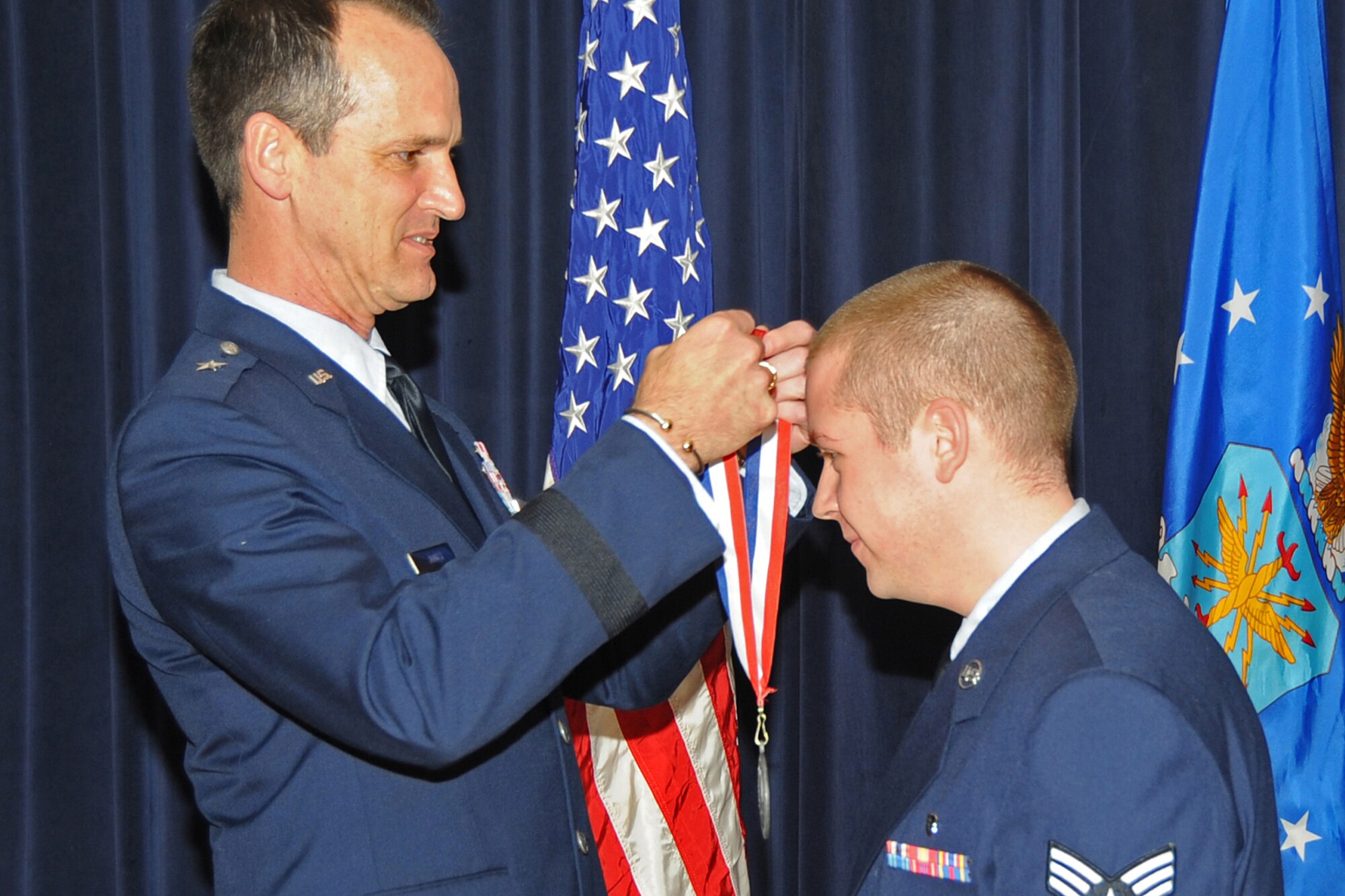 OFFUTT AIR FORCE BASE, Neb. -- Brig. Gen. James Jones, 55th Wing commander, places a medal over the head of Senior Airman Brian Reddish of the 55th Medical Group for the 55th Wing Annual Awards Medallion Ceremony at the Patriot Club Feb. 26th. The ceremony honor those nominated for the wing's annual awards. 

 U.S. Air Force Photo by Jeff Gates