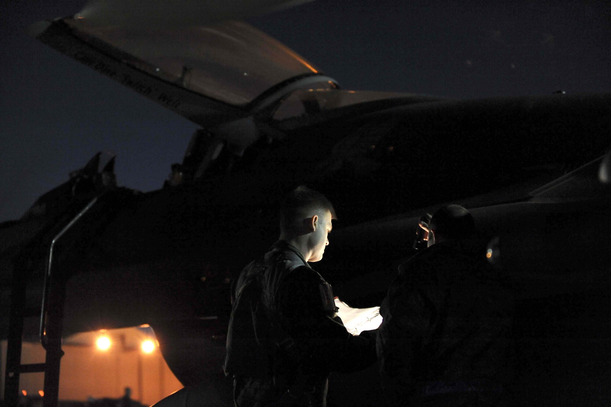 NELLIS AIR FORCE BASE, Nev. -- Capt. Mike Willhide, (left) 157th Fighter Squadron F-16 Fighting Falcon pilot, reviews his pre-flight paperwork with Airman 1st Class Patrick Densford, 52nd Aircraft Maintenance Squadron F-16 Fighting Falcon crew chief, before night flying operations during Red Flag 09-3 at Nellis Air Force Base, Nev., Feb. 26, 2009. Red Flag is a multi-national exercise providing a realistic environment to practice combat scenarios. Captain Willhide is deployed here from McEntire Joint National Guard Base, S.C. Airman Densford is deployed here from Spangdahlem Air Base, Germany.  (U.S. Air Force Photo by Senior Airman Larry E. Reid Jr.)