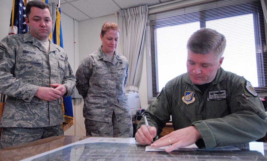 Senior Master Sgt. Jeremy Simpson, 8th Maintenance Squadron, and Captain Dawn Baker, 8th Logistic Readiness Squadron watch as Col. J.D. "Wolf" Harris, 8th Fighter Wing Commander, signs up to donate to the Air Force Assistance Fund at Kunsan Air Base, Republic of Korea, Mar. 3, 2009. (U.S. Air Force Photo/Senior Airman Gustavo Gonzalez)