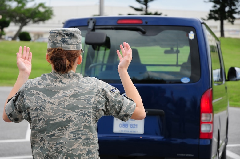 Airman 1st Class Amanda Grabiec, 18th Wing Public Affairs, demonstrates the proper technique to spot a vehicle while reversing at Kadena Air Base, Japan, March 4, 2009. Simple safety precautions such as this can reduce the number of preventable traffic accidents involving government vehicles. (U.S. Air Force photo/Airman 1st Class Chad Warren)