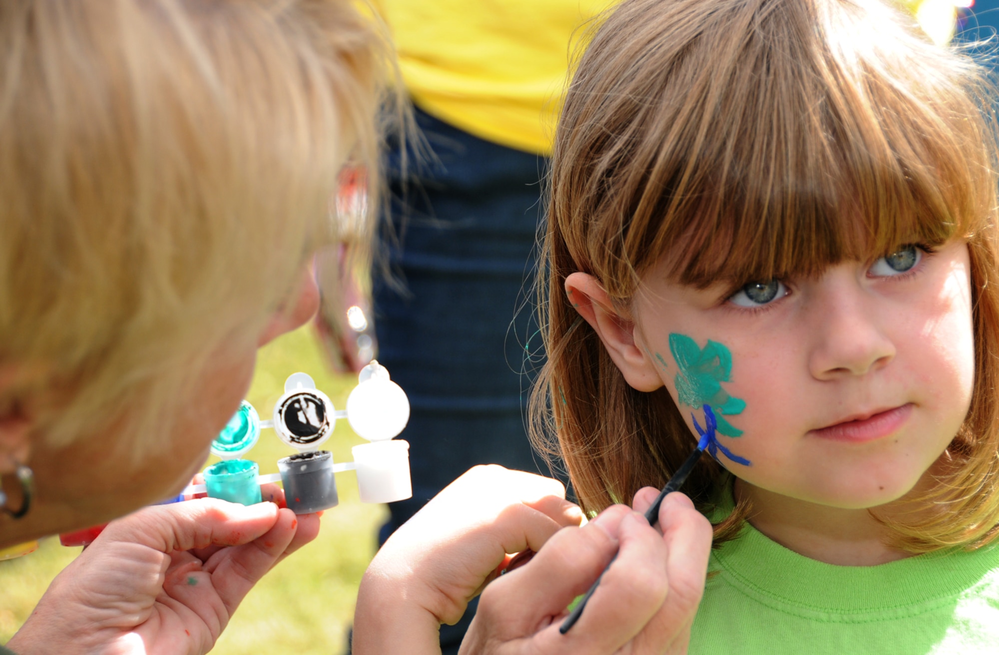 Genia Crane, American Red Cross, paints a flower on Elizabeth Speed’s face at the Mardi Gras get-together for families of deployed members hosted by the airman and family readiness center.  The 8-year-old is the daughter of Kendra and Tech. Sgt. David Speed, 334th Training Squadron.  He’s scheduled to return from Kuwait later this month.