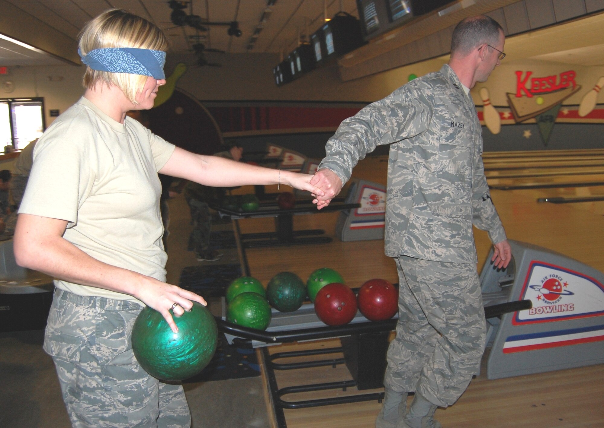 Captain Mazey helps Staff Sgt. Cassandra Key, 81st MDSS, grasp a bowling ball before leading her to the lane to bowl — blindfolded.  (U.S. Air Force photo by Steve Pivnick)