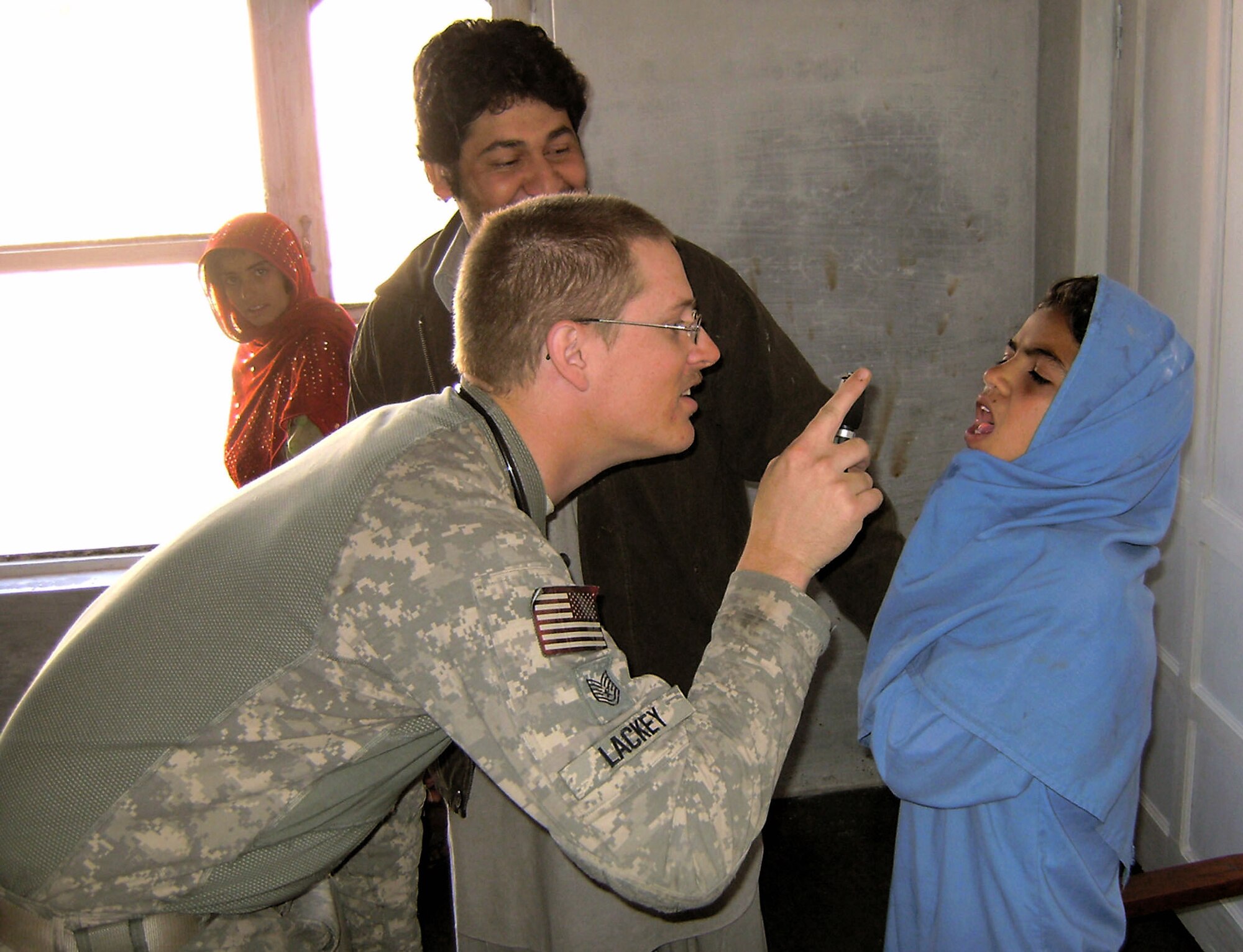 Technical Sgt. Joshua Lackey examines an Afghan girl from the Hope of Mother School, Feb. 24 in the Surkh Rod District of Afghanistan. American medics treated more than 120 people during the medical assistance operation at the school and clinic. Sergeant Lackey is a medic with the provincial reconstruction team in Afghanistan's Nangarhar province. (U.S. Air Force photo/Capt. Dustin Hart) 
