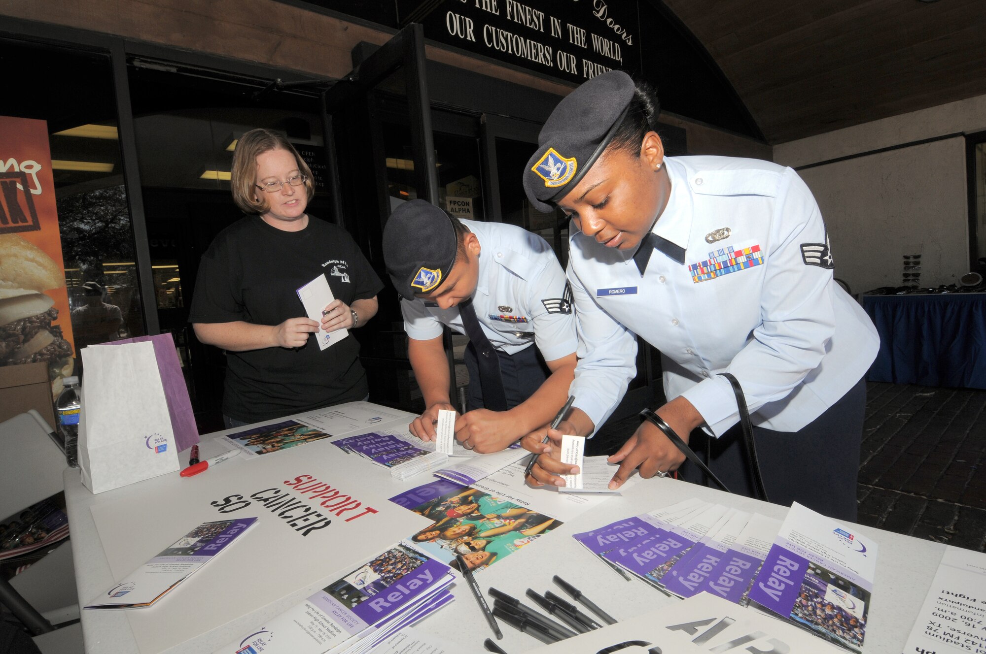 Senior Airmen Janice Romero and Jefferson Reyes, 12th Security Forces Squadron, donate March 4 to the Greater Randolph Relay for Life in support of the American Cancer Society. Airmen setup a booth outside the base exchange to sell "luminarias" that will light the track for walkers in the relay that takes place 7 p.m. to 7 a.m. on May 16 at Judson High School. For more information on the Relay for Life, visit www.relayforlife.org/greaterrandolphtx. (U.S. Air Force photo by Melissa Peterson)