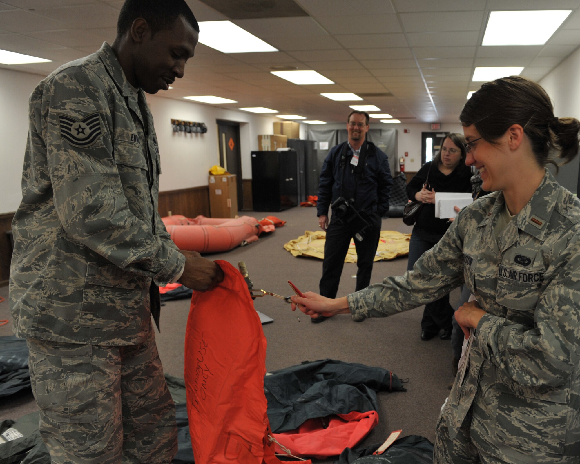 MOODY AIR FORCE BASE, Ga. -- Tech. Sgt. David Edwards, 347th Operations Support Squadron, NCO in-charge of aircrew flight equipment, demonstrates how to open an inflated single man survival raft for reporters from the Valdosta Daily Times here March 3. 2nd Lt. Chelsey Garrison, 23rd Wing, deputy chief of public affairs, pulls a lever to release carbon dioxide from a small canister which is used to inflate the raft. (U.S. Air Force photo by Senior Airman Javier Cruz Jr.)
