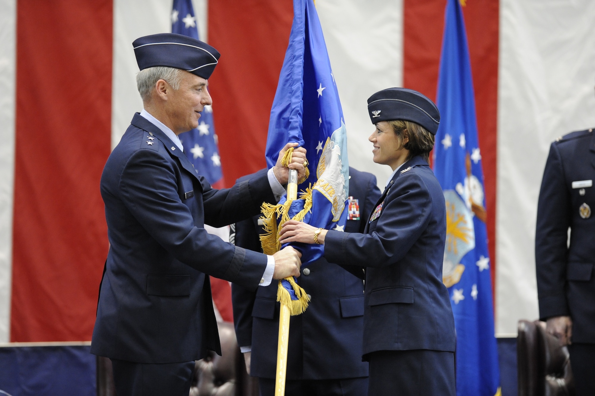 Maj. Gen. Winfield Scott III, 18th Air Force commander, passes the wing flag to Col. Gina Grosso, the new 87th Air Base Wing commander, during an assumption of command ceremony here March 3. Colonel Grosso will be the first joint base commander of JB McGuire-Dix-Lakehurst. (U.S. Air Force photo/Carlos Cintron)  