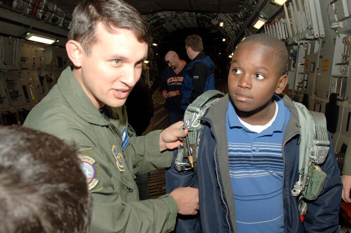 Senior Airman Mitch Thompson explains to Keshun Douglas when to pull the automatic release handle on a parachute during a tour of a static C-17 on the flightline here March 3. Students from Devon Forest Elementary school in Goose Creek, S.C. were given the opportunity to take part in this field trip to inspire them to succeed and realize that they can achieve personal goals if they work hard towards accomplishing them. Senior Airman Thompson is a C-17 loadmaster and joint airdrop inspector assigned to the 437th Operations Support Squadron. (U.S. Air Force photo/Staff Sgt. Marie Cassetty)