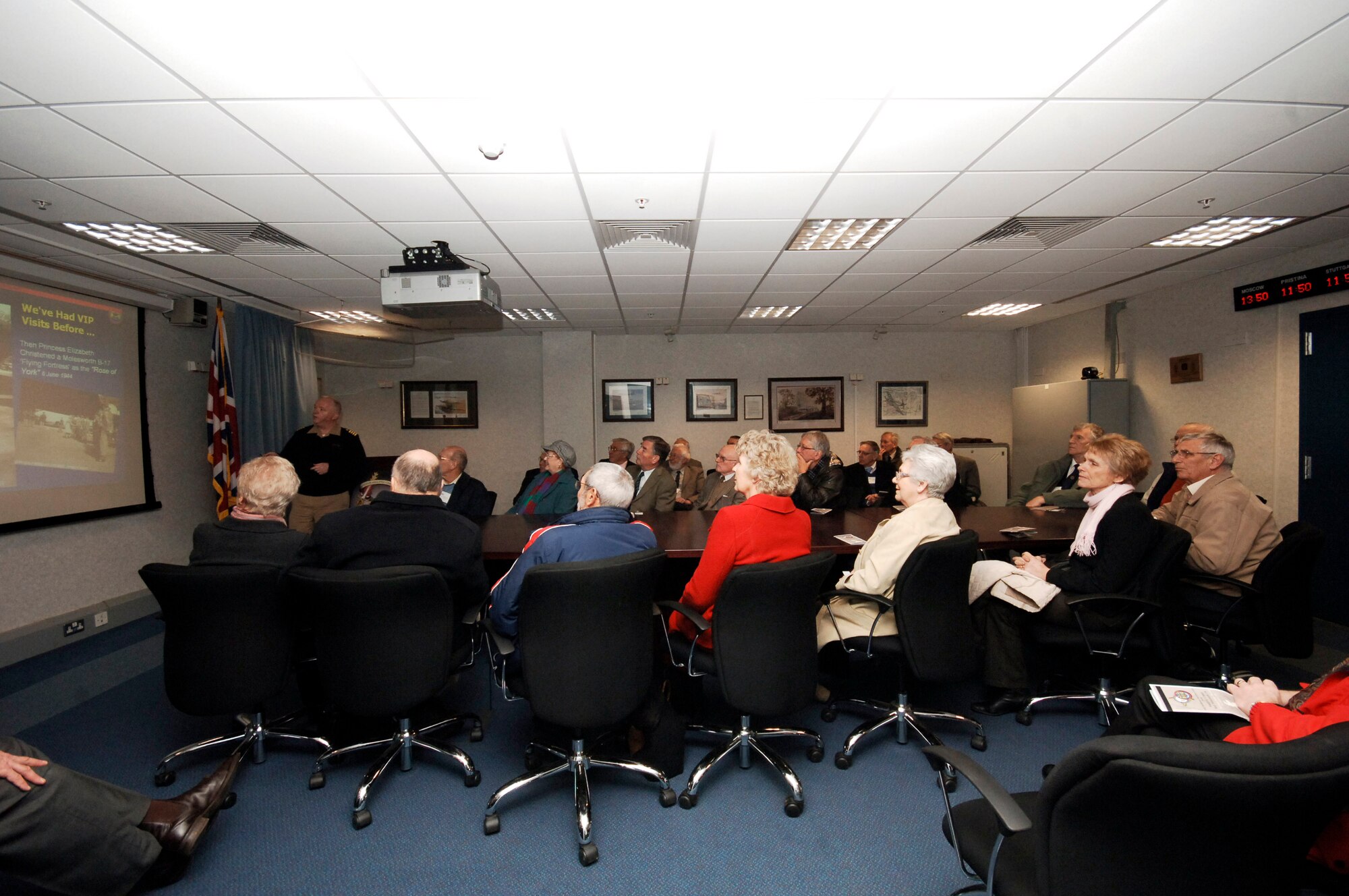 Navy Captain Henry J. "Harry" Babin, Deputy Commander of the JIOCEUR Analytic Center  briefs the Nene Valley PROBUS business group at RAF Molesworth during a visit by the group to the base on February 27th.  In the photo the Captain is reviewing a slide describing the July 1944 visit of then-Princess Elizabeth during which she christened a B-17 Flying Fortress aircraft as "Rose of York."  HRH Princess Elizabeth accompanied the King and Queen on the visit. (U.S. Air Force Photo by Staff Sgt Rachel A. Goff)