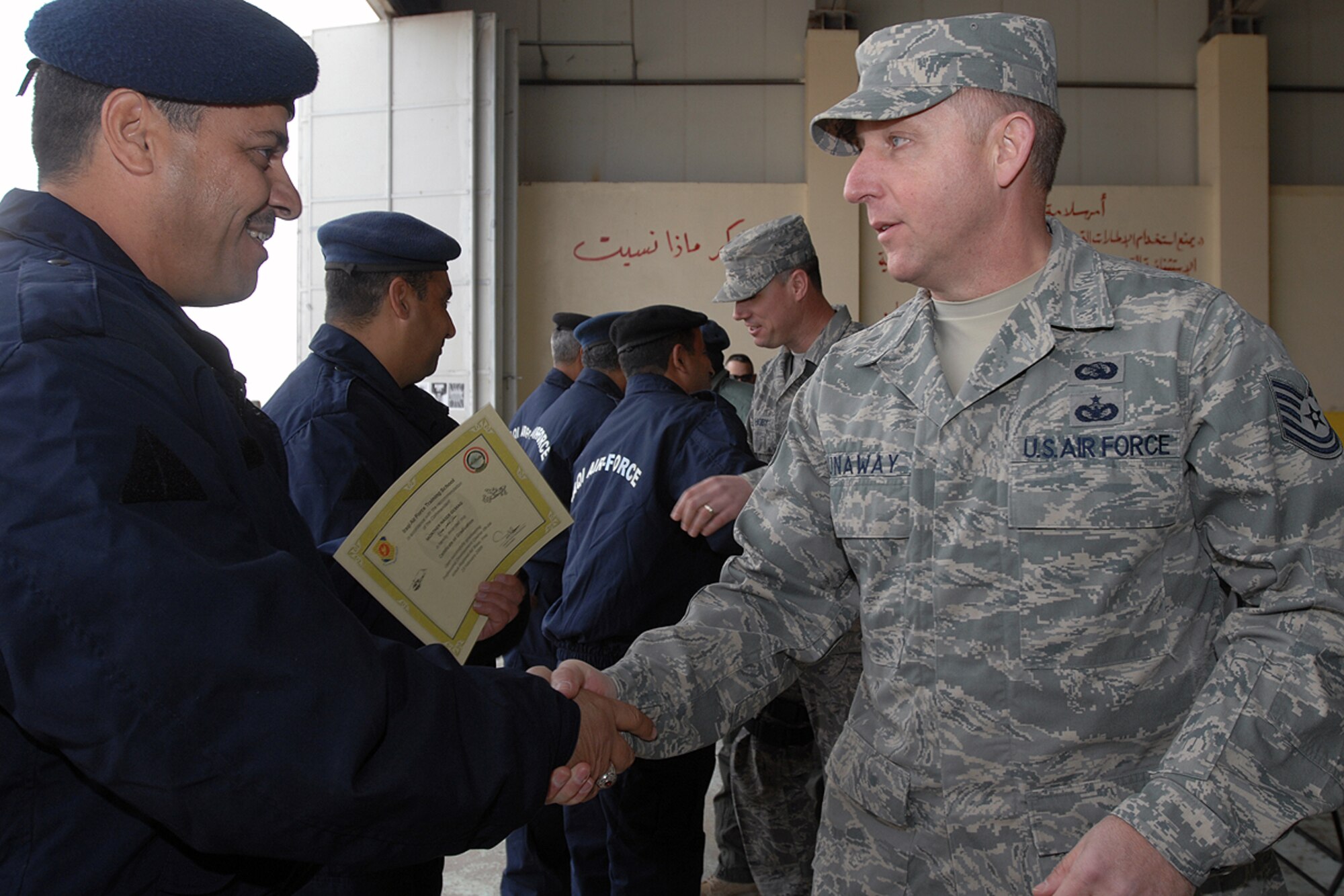 Professional Military Education instructors Tech. Sgt. Rick Dunaway, deployed from Maxwell AFB, Ala., and Tech. Sgt. Michael Higby, deployed from Kapaun Air Base, Germany, congratulate Iraqi Air Force enlisted graduates of a PME course taught here recently. Sergeant Higby, an Anchorage, Alaska native and Sergeant Dunaway, a Russellville, Ark., native are traveled to Kirkuk RAB from Camp Taji, Iraq, to teach the Airmen enlisted management, team building and leadership skills. (U.S. Air Force photo / Staff Sgt. Eunique Stevens)