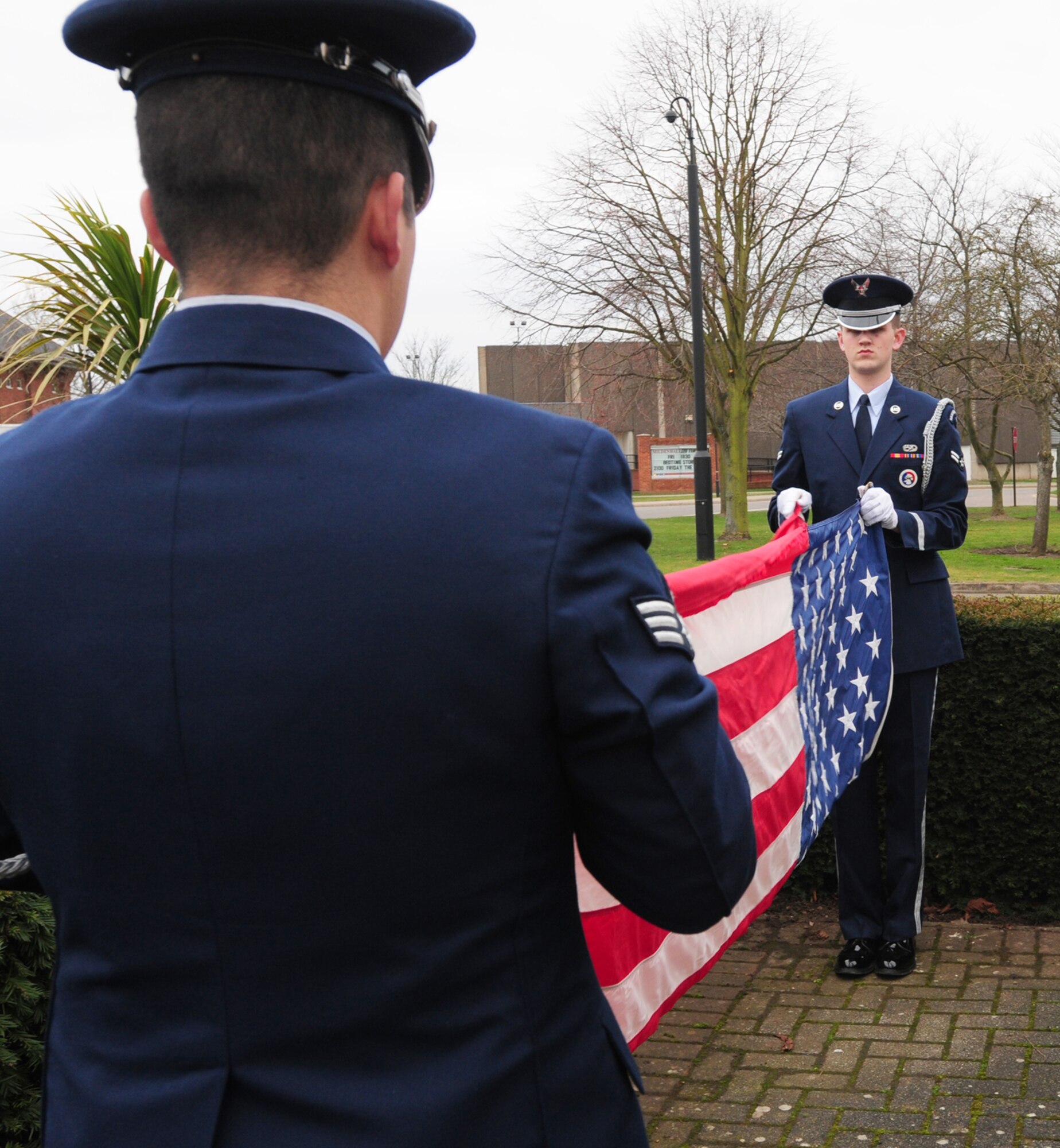 Team Mildenhall Honor Guard members, Senior Airman Robert Lysholm, left, 100th Civil Engineer Squadron, and Airman 1st Class Gianni Rocco, 100th Maintenance Squadron, fold the Stars and Stripes flag Feb. 27, 2009, at the flagpoles outside the 100th Air Refueling Wing headquarters building during a retreat. The 100th Communications Squadron performed the retreat, which is a Team 5/6-sponsored event. Each month, a different squadron performs the retreat during the playing of the national anthems. (U.S. Air Force photo by Karen Abeyasekere)
