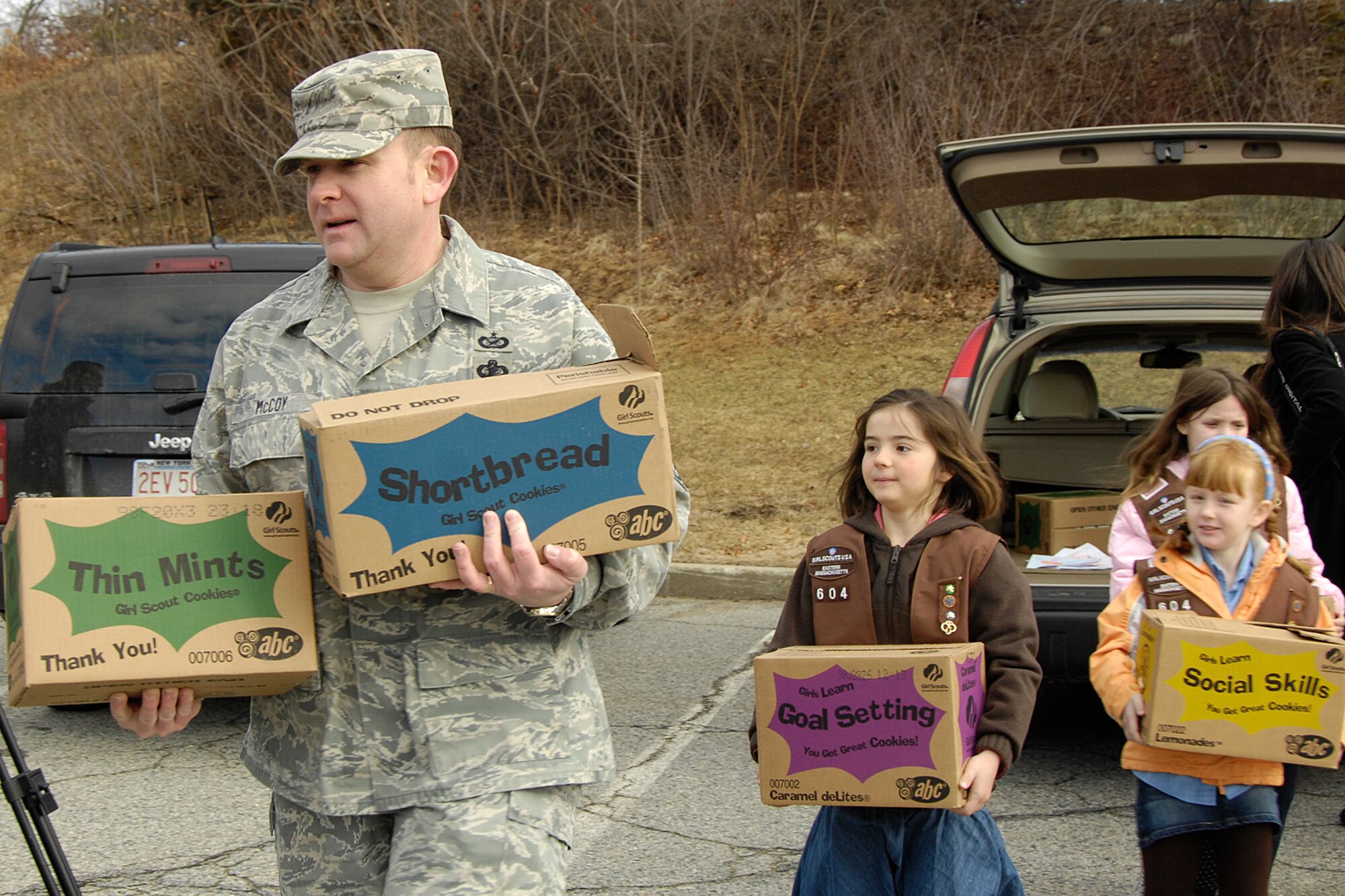 HANSCOM AIR FORCE BASE, Mass. – Chief Master Sgt. Michael McCoy (left), 66th Mission Support Group superintendent, helps Girl Scouts unload some of the more than 15,000 boxes of cookies that were delivered to Hanscom on Feb. 28. The cookies will provide a “taste of home” to deployed Airmen, Soldiers, Sailors and Marines.  (U.S. Air Force photo by Linda LaBonte Britt)