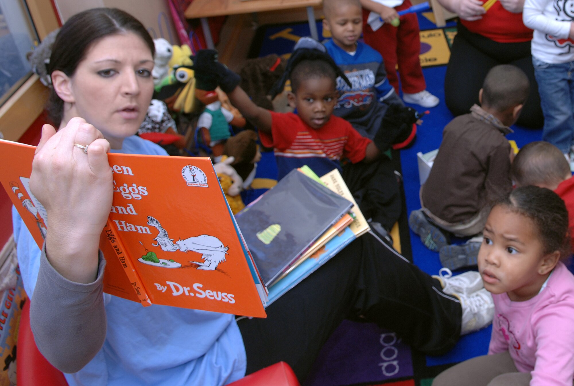 Adri Hern, Incirlik Child Development Center program assistant, reads the book “Green Eggs and Ham” by Dr. Seuss to a group of children, March 2 at the Child Development Center’s “Seussentenial.” The “Seussentenial” is a celebration of author Dr. Seuss’ 100th birthday, if he were alive today. Theodor Seuss Geisel wrote over 60 children’s books under his pen name, Dr.Seuss. (U.S. Air Force photo/Senior Airman Erica Stewart)