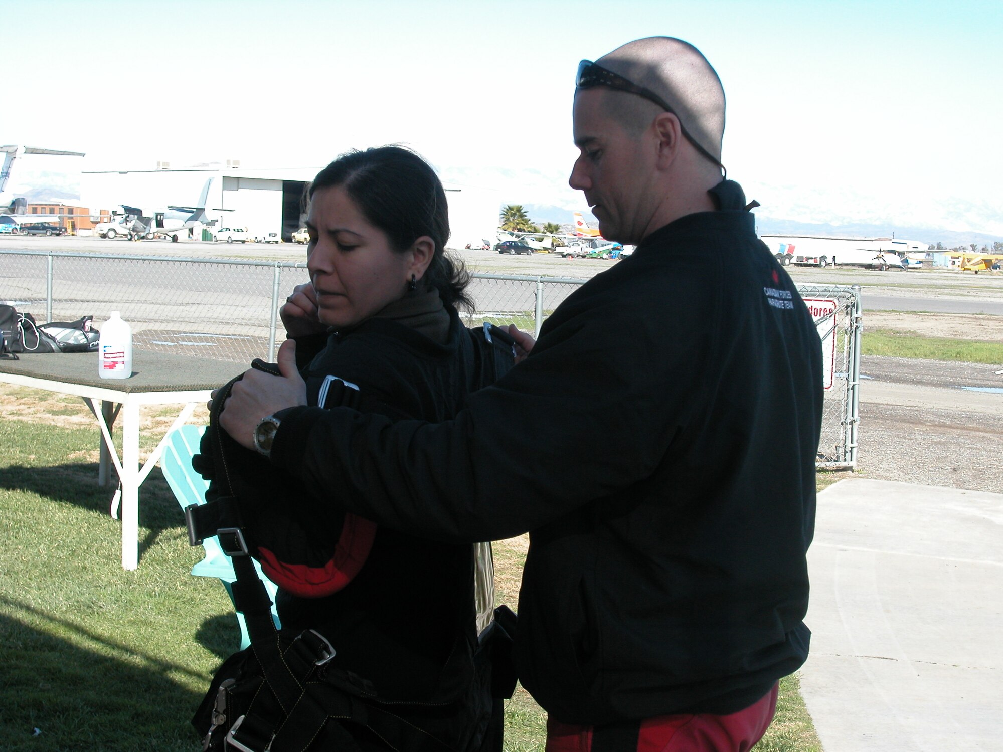 While training for their upcoming demonstration season, the Canadian SkyHawks gave two 452 AMW Public Affairs employees tandem jumps during their practice sessions.  CorporalSebastien Pinard, parachute rigger for Canadian SkyHawks parachuting team, and Ms. Valerie Palacios, community relations expert, assists Ms. Palacios don her safety gear for her tandem sky dive. (U.S. Air Force photo by
Staff Sgt Megan Crusher)