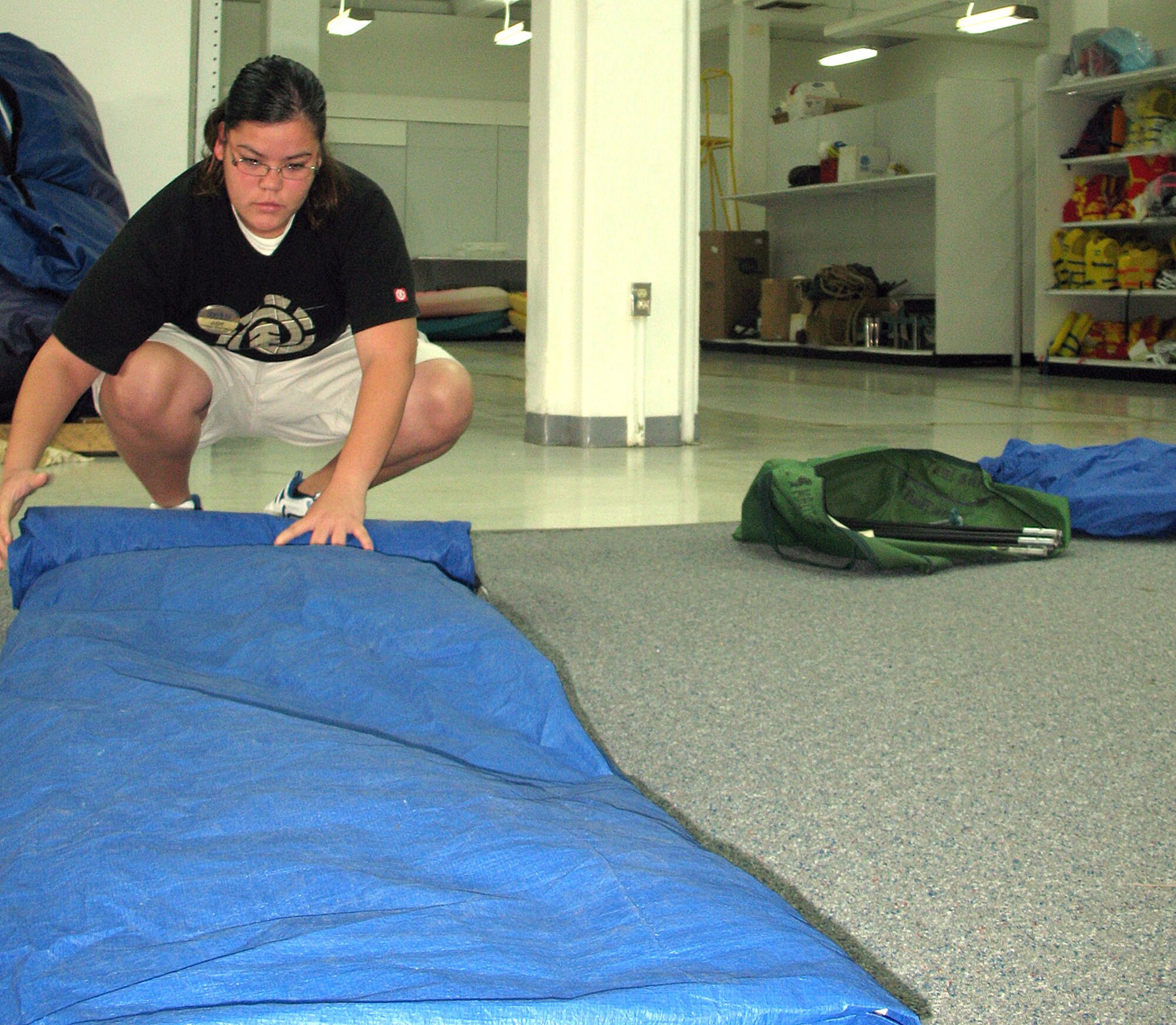 ANDERSEN AIR FORCE BASE, Guam -- Judy Taimanglo, 36th Force Support Squadron civilian and Outdoor Recreation assistant, folds a rental tent for storage in Outdoor Recreation's new location, Building 25018, Mar. 4. The building previously housed the furniture shop. (U.S. Air Force photo by Airman 1st Class Carissa Wolff)