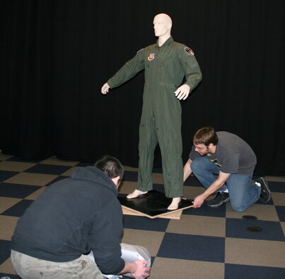 Brenton Mathews and David Pent, employees of Activision subsidiary Raven Software, position a mannequin with a flight suit from the 115th Fighter Wing in order to get a 3-D scan for use in current and possible future video games. Raven Software tries to scan authentic gear for use in their games to save artist time and also to extract a very high level of detail and authenticity for their games. (U.S. Air Force photo by Staff Sgt. Jon LaDue) 
