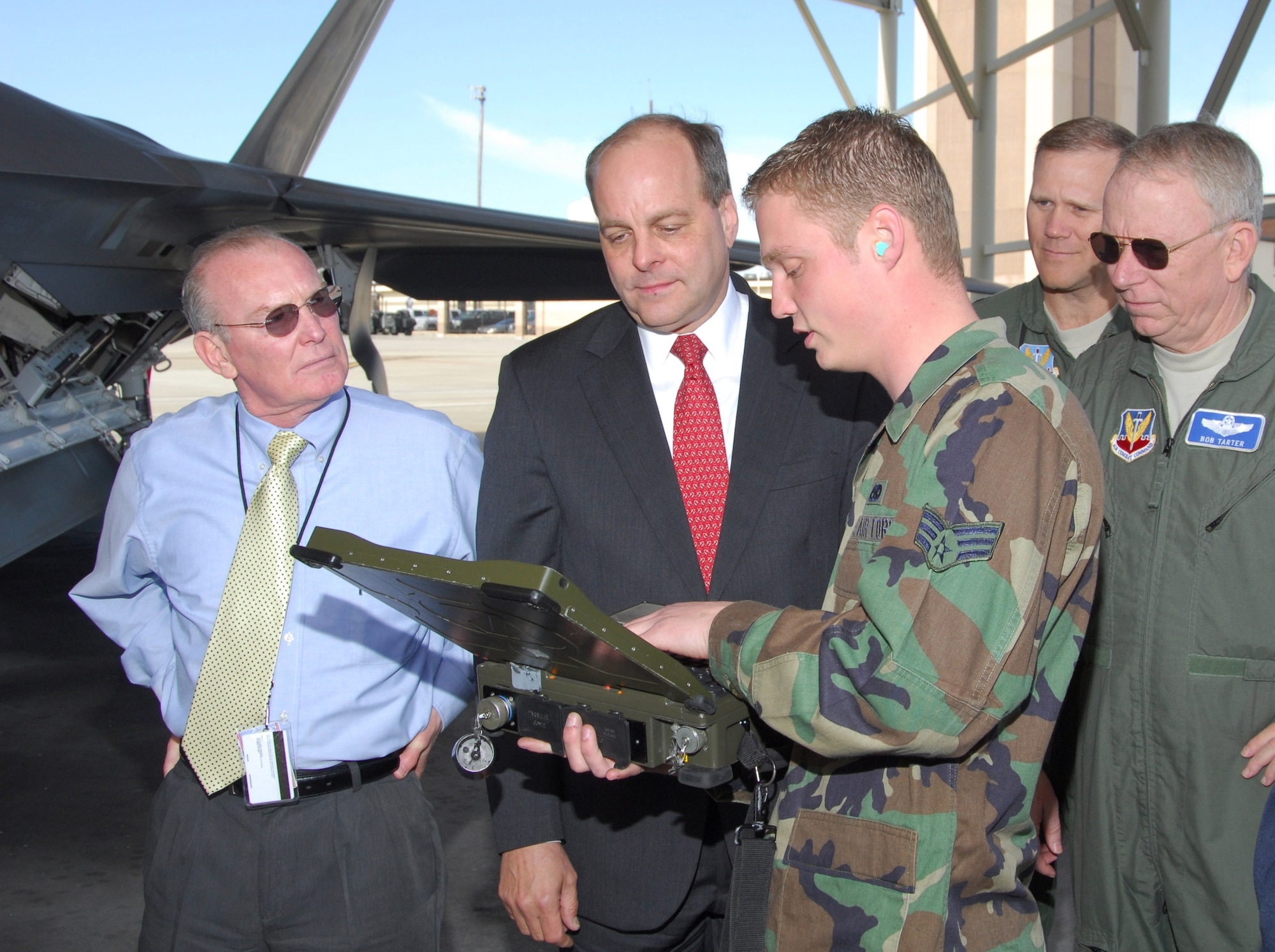 Steven Flickinger, FAA Cessna Citation co-pilot, Hank Krakowski, FAA office of safety, Brig. Gen. Jeffrey Lofgren, 1st Air Force vice commander, and Brig. Gen. Robert Tarter, the mobilization assistant to the commander, AFNORTH and vice president, office of safety, FAA Air Traffic Organization, listen as Senior Airman Jacob Moen, F-22 Raptor dedicated assistant crew chief, explains aircraft maintenance procedures during a visit of senior-level Federal Aviation Administration officials Feb. 12.