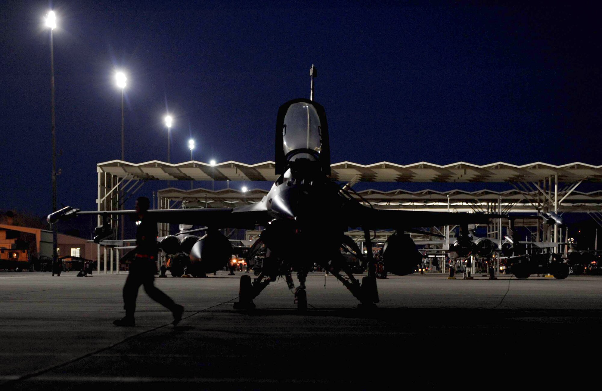 An F-16 Fighting Falcon crew chief assigned to the 52nd Aircraft Maintenance Squadron from Spangdahlem Air Base, Germany, walks past his mission-ready jet before night flying operations during Red Flag 09-3 Feb. 26 at Nellis Air Force Base, Nev. Red Flag is a multinational exercise providing a realistic environment to practice combat scenarios. (U.S. Air Force photo/Senior Airman Larry E. Reid Jr.) 
