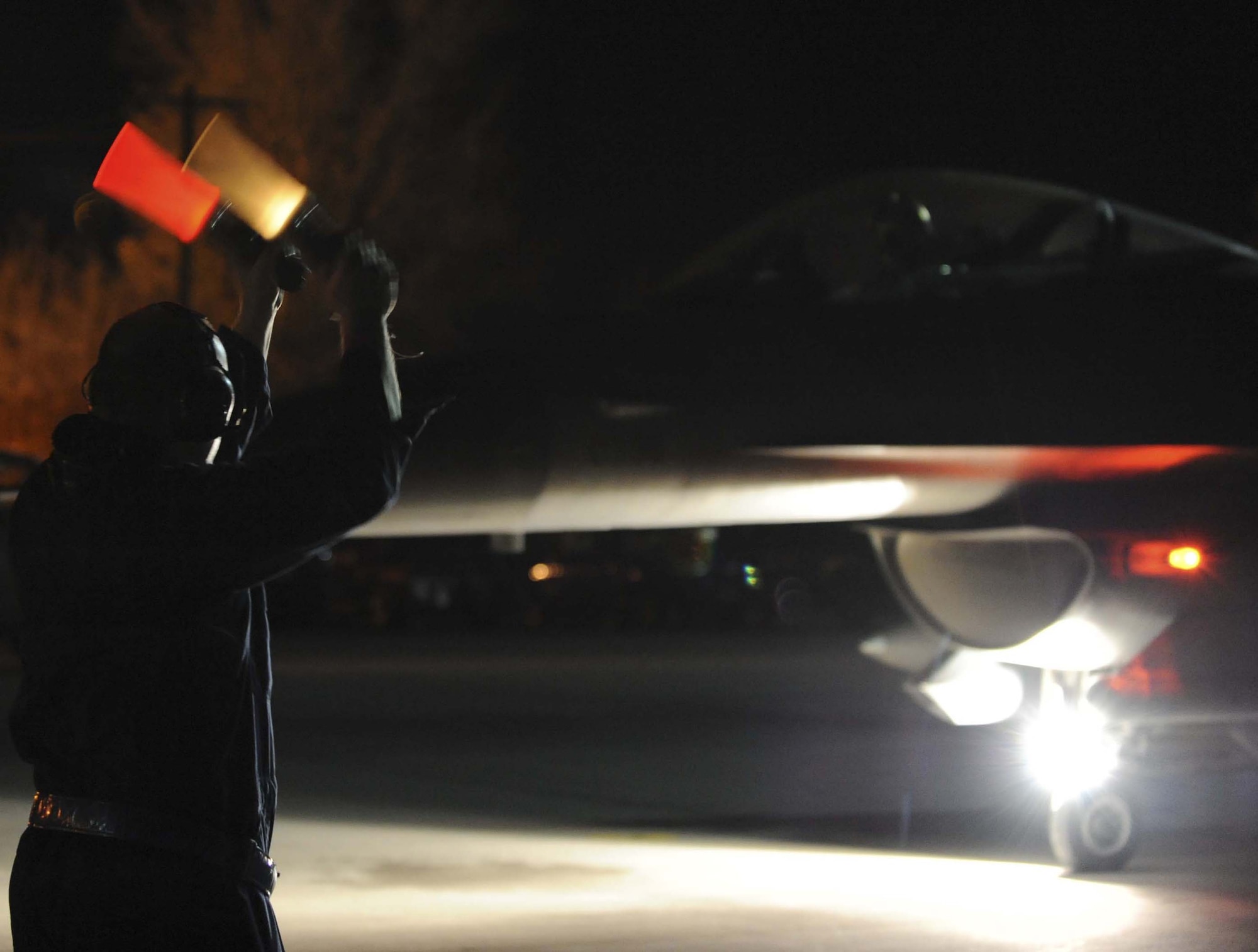 Airman 1st Class Patrick Densford marshals Capt. Mike Willhide in an F-16 Fighting Falcon for a night flying operation during Red Flag 09-3 Feb. 26 at Nellis Air Force Base, Nev. Red Flag is a multinational exercise providing a realistic environment to practice combat scenarios. Airman Densford is a 52nd Aircraft Maintenance Squadron F-16 crew chief deployed from Spangdahlem Air Base, Germany. Captain Willhide is a 157th Fighter Squadron F-16 pilot deployed from McEntire Joint National Guard Base, S.C. (U.S. Air Force photo/Senior Airman Larry E. Reid Jr.) 

