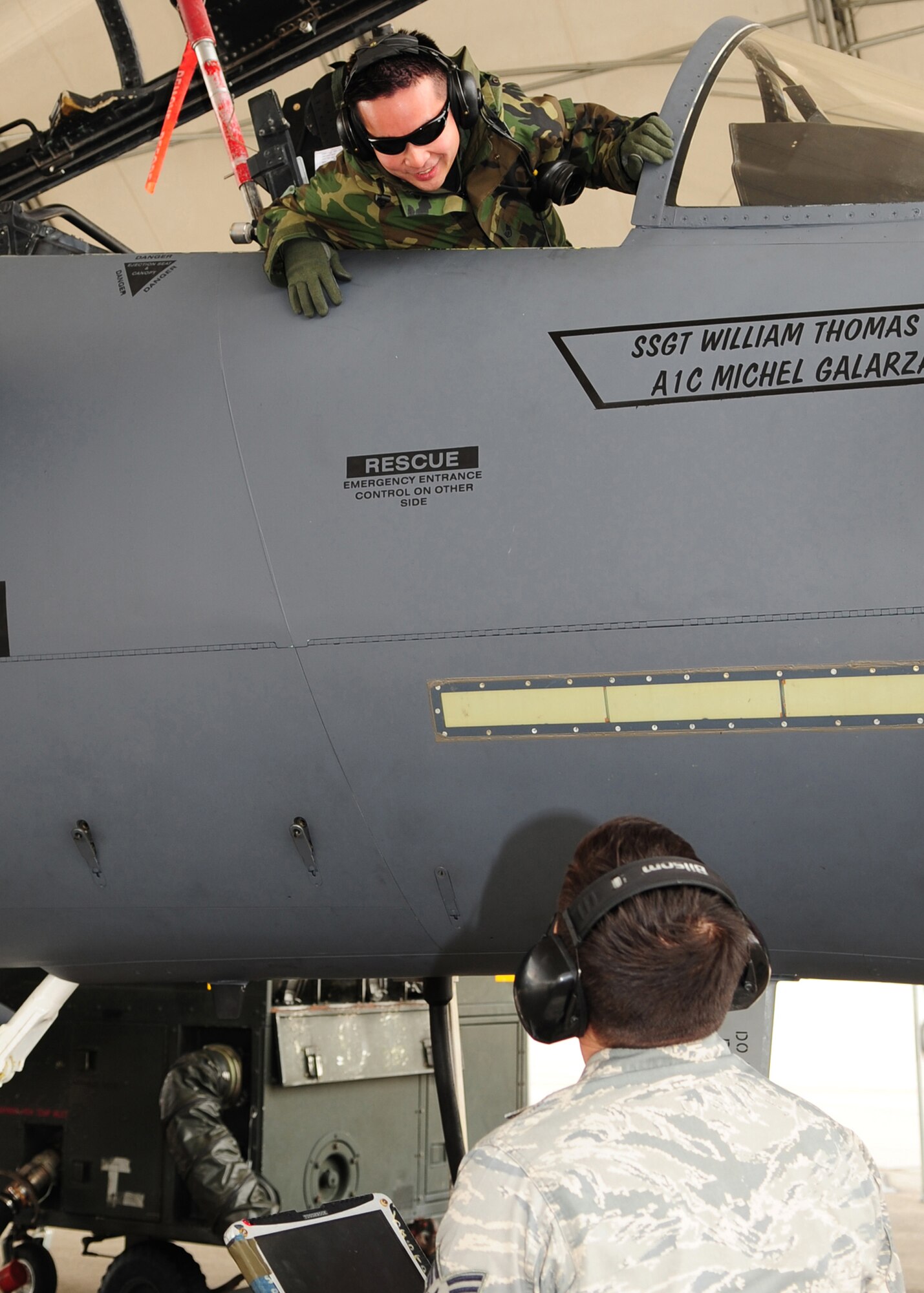 Senior Airman Jon Meyers gives directions to Staff Sgt. Hai Ho, 336th Aircraft Maintenance Squadron, who is sitting in the cockpit of the F-15E Strike Eagle under a flight line shelter on Seymour Johnson Air Force Base, N.C., March 2. The shelters main purpose is to prevent sun damage and minimize the amount of rain that reaches the aircraft. (U.S. Air Force Photo by Airman 1st Class Rae A. Perry)