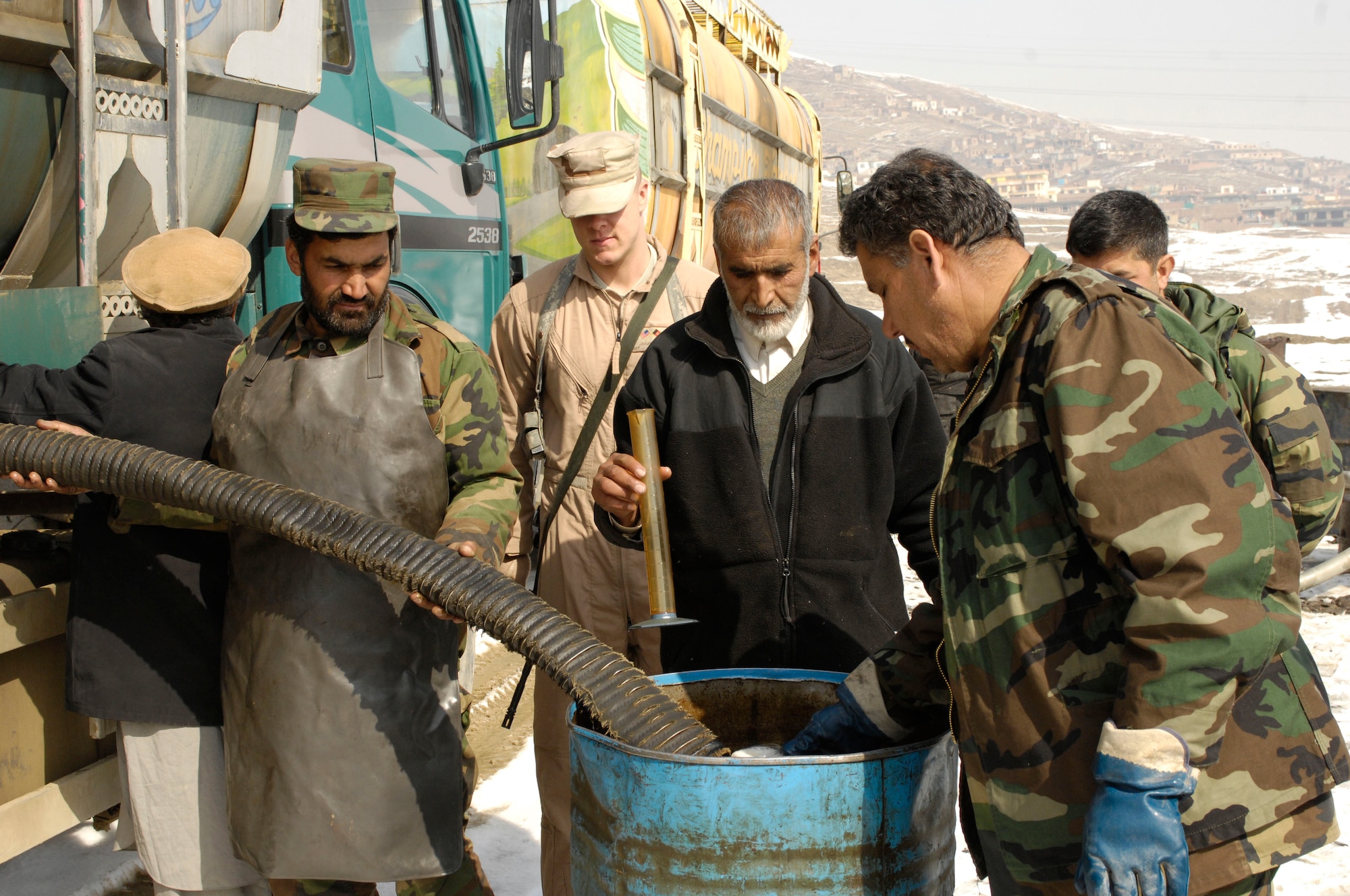 Afghanistan National Army Lt. Col. Mohammad Adris, operations officer and fuels tester, captures fuel in a clear glass coffee mug Feb. 17 as its offloaded from a fuels truck prior to accepting delivery. The inspector raises the mug, once full, looking for sediment.  No sediment? Then the fuel is "pure."  (U.S. Air Force photo/ Maj. Carie A. Parker)
