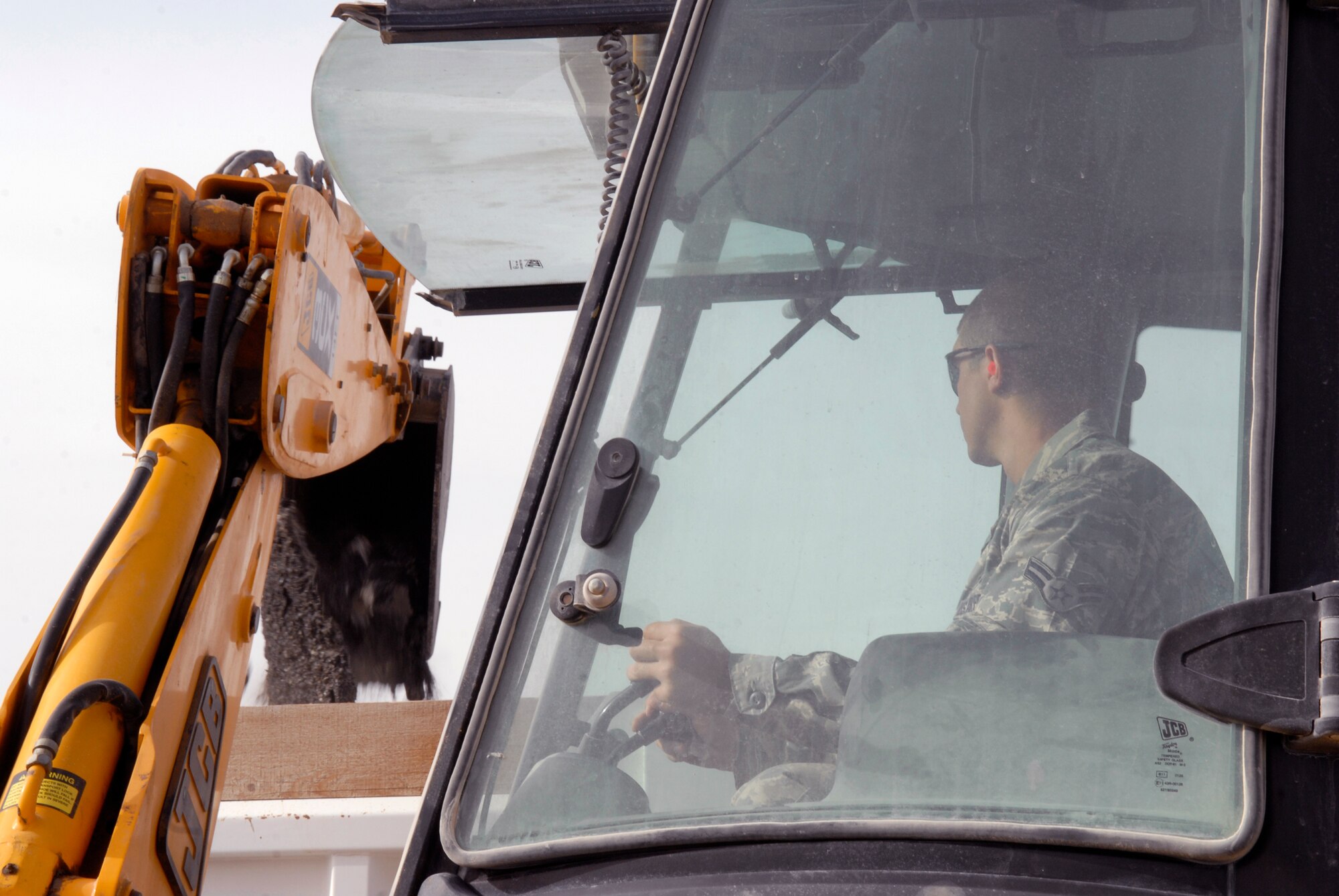 Airman 1st Class Andrew Sanders, a 379th Expeditionary Civil Engineer Squadron Pavements and Equipment Journeyman, dumps broken asphalt with a backhoe in preparation for a patch repair on the flightline, Mar. 4, 2009, at an undisclosed location in Southwest Asia.  Airman Sanders hails from Payson, Ariz. and is deployed from Spangdahlem Air Base, Germany in support of Operations Iraqi and Enduring Freedom and Combined Joint Task Force - Horn of Africa.  (U.S. Air Force Photo by Senior Airman Andrew Satran/Released)