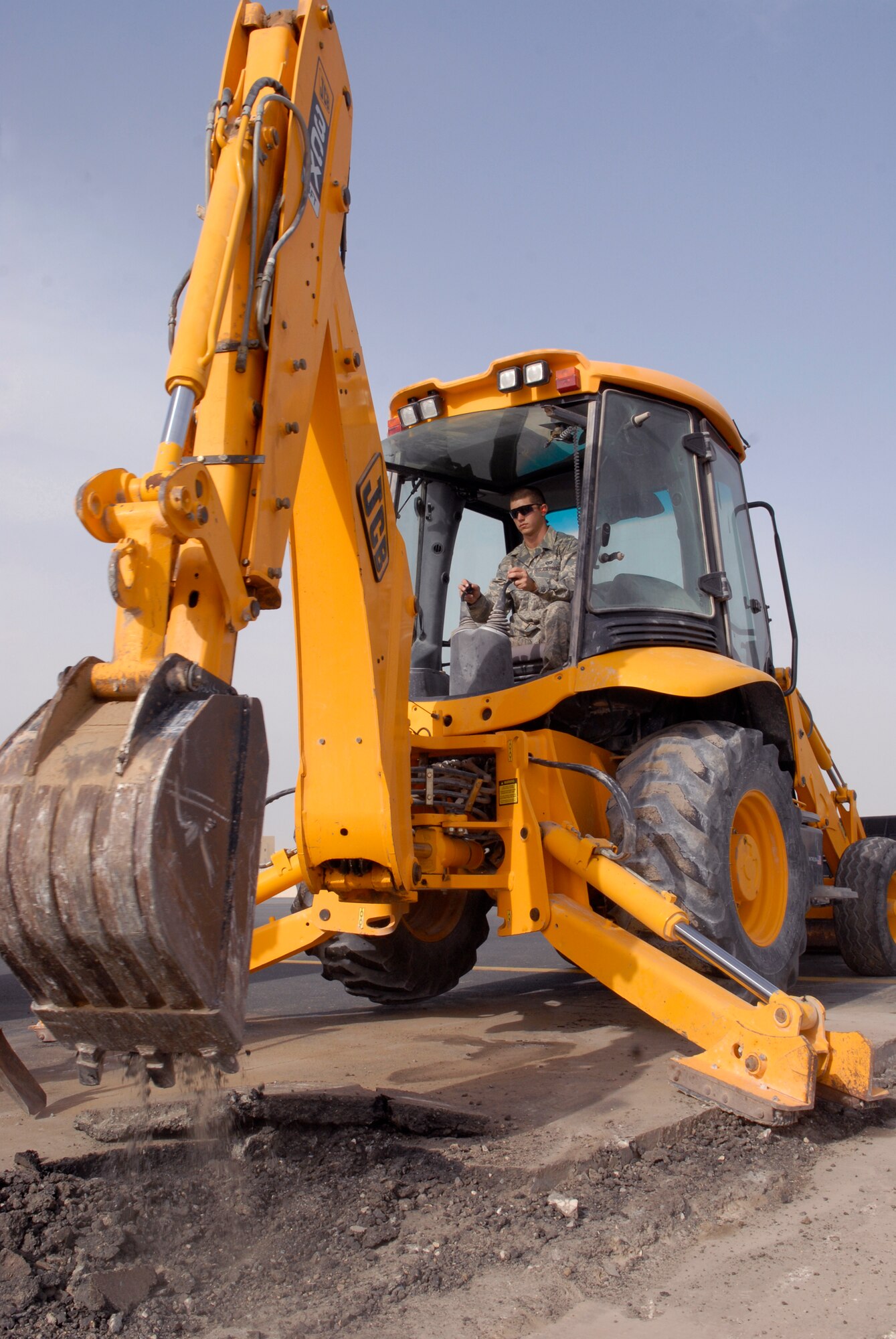 Airman 1st Class Andrew Sanders, a 379th Expeditionary Civil Engineer Squadron Pavements and Equipment Journeyman, breaks up asphalt with a backhoe in preparation for a patch repair on the flightline, Mar. 4, 2009, at an undisclosed location in Southwest Asia.  Airman Sanders hails from Payson, Ariz. and is deployed from Spangdahlem Air Base, Germany in support of Operations Iraqi and Enduring Freedom and Combined Joint Task Force - Horn of Africa.  (U.S. Air Force Photo by Senior Airman Andrew Satran/Released)