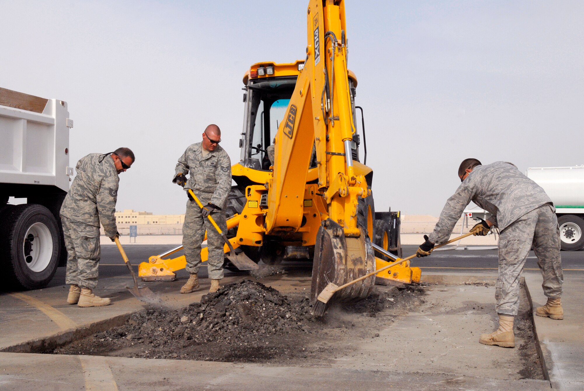 Airmen with the 379th Expeditionary Civil Engineer Squadron Heavy Equipment shop help load asphalt dug up in preparation for a patch repair on the flightline, Mar. 4, 2009, at an undisclosed location in Southwest Asia in support of Operations Iraqi and Enduring Freedom and Combined Joint Task Force - Horn of Africa.  (U.S. Air Force Photo by Senior Airman Andrew Satran/Released)