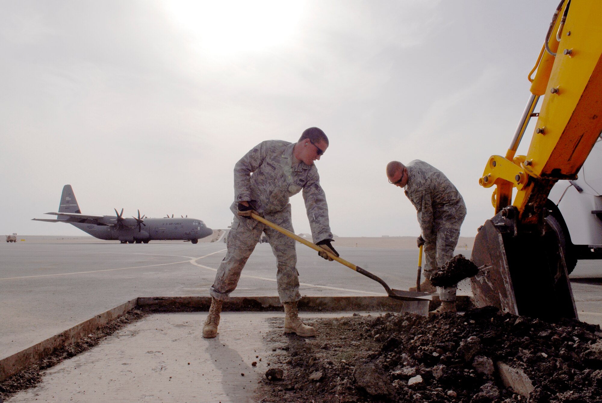 Senior Airman Drew Harrison and Staff Sergeant Byron Harrison, 379th Expeditionary Civil Engineer Squadron Heavy Equipment Operators, help move asphalt in preparation for a patch repair on the flightline, Mar. 4, 2009 at an undisclosed location in Southwest Asia.  Airman Harrison hails from Austin, Texas and is deployed from Lackland Air Force Base, Texas.  Staff Sgt. Icenogle hails from Shelbyville, Ind. and is deployed from Scott Air Force Base, Ill.  Both are deployed in support of Operations Iraqi and Enduring Freedom and Combined Joint Task Force - Horn of Africa.  (U.S. Air Force Photo by Senior Airman Andrew Satran/Released)