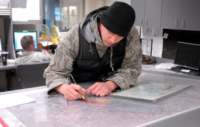 Senior Airman Allen Russo updates the plot board in the 437th Security Forces Squadron here March 4. The plot board is updated six times a day to show aircraft location for security purposes. Airman Russo is a patrolman assigned to the 437 SFS.
