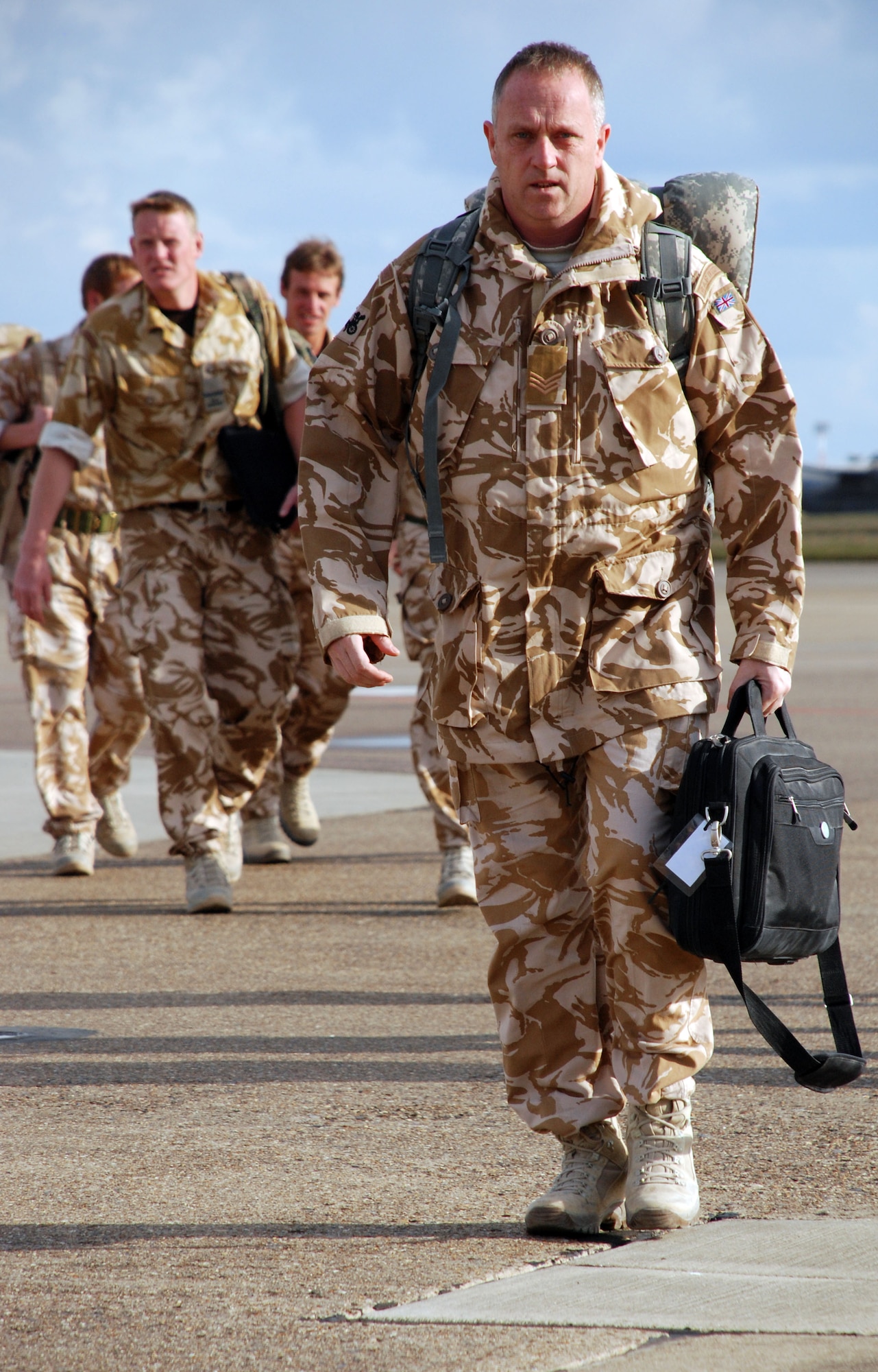 Royal Air Force Sergeant Ady Shaw carries his deployment gear from a military charter plane to the customs area at RAF Mildenhall March 4 after a six-month deployment to Kandahar Air Base, Afghanistan.  About 150 RAF servicemembers landed at RAF Mildenhall instead of their typical point of return, shaving about five hours off their journey home to RAF Honington.  (U.S. Air Force photo by Staff Sgt. Austin M. May)