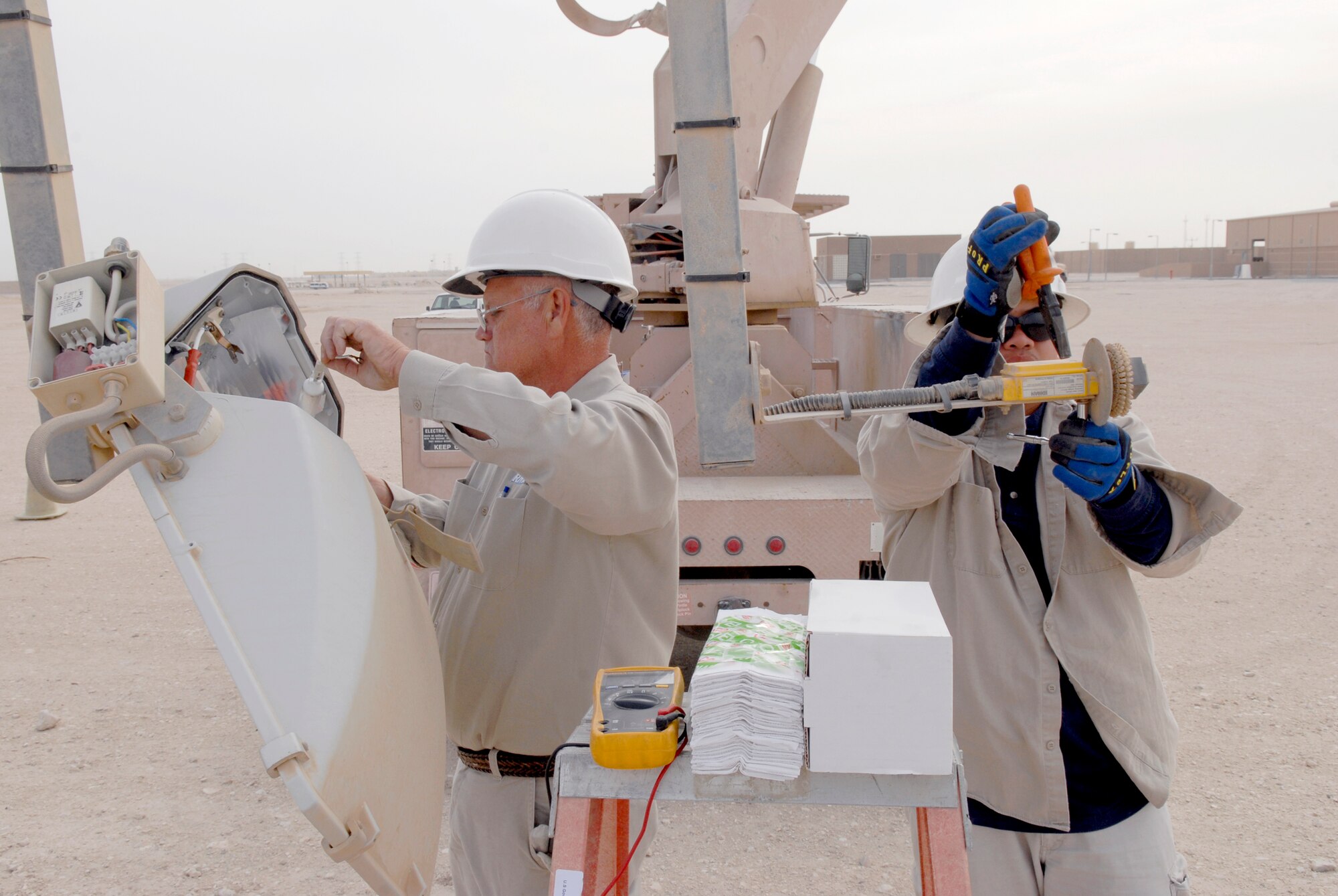 John Nettles and Jimmy Mercado, 379th Civil Engineer Squadron Readiness Management Support (RMS) Contractors, repair a ramp parking light tower on the outer edge of the flightline, Mar. 4, 2009, at an undisclosed location in Southwest Asia.  John Nettles hails from McComb, Miss.  Jimmy Mercado hails from Santa Rita Pampanga, Philippines.  Both are here in support of Operations Iraqi and Enduring Freedom and Combined Joint Task Force - Horn of Africa.  (U.S. Air Force photo by Senior Airman Andrew Satran/released)