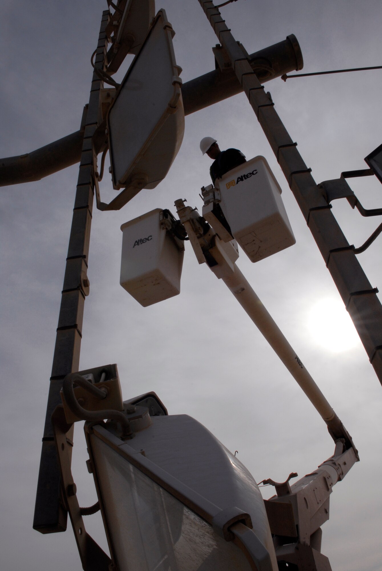 J C Corbin, a 379th Expeditionary Civil Engineer Squadron Readiness Management Support (RMS) contractor, hoists up to repair parking ramp lights on the outer edge of the flightline, Mar. 4, 2009, at an undisclosed location in Southwest Asia.  Mr. Corbin hails from Toledo, Ohio and is here in support of Operations Iraqi and Enduring Freedom and Combined Joint Task Force - Horn of Africa.  (U.S. Air Force Photo by Senior Airman Andrew Satran/Released)