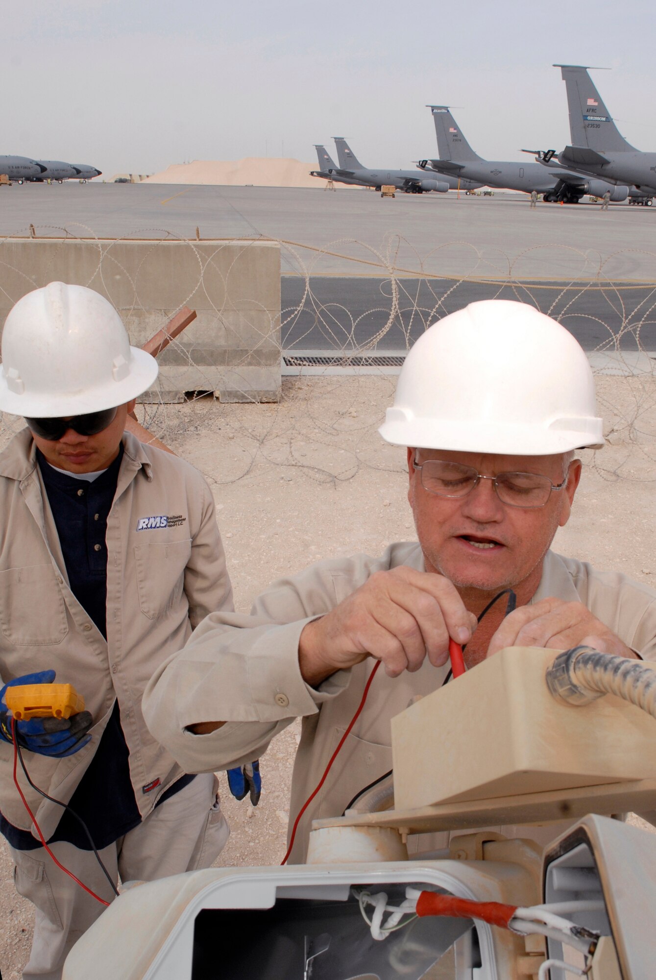 Jimmy Mercado and John Nettles, 379th Civil Engineer Squadron Readiness Management Support (RMS) Contractors, check the voltage for a repair job on ramp parking lights on the outer edge of the flightline Mar. 4, 2009, at an undisclosed location in Southwest Asia.  Jimmy Mercado hails from Santa Rita Pampanga, Philippines.  John Nettles hails from McComb, Miss.  Both are here in support of Operations Iraqi and Enduring Freedom and Combined Joint Task Force - Horn of Africa.  (U.S. Air Force photo by Senior Airman Andrew Satran/released)