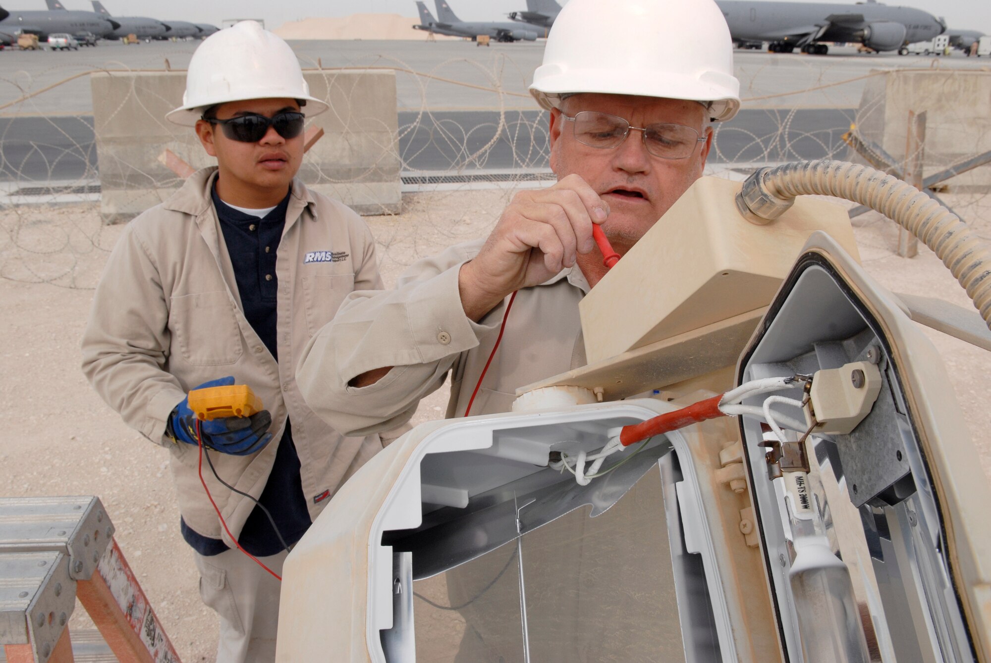Jimmy Mercado and John Nettles, 379th Civil Engineer Squadron Readiness Management Support (RMS) Contractors, check the voltage for a repair job on ramp parking lights on the outer edge of the flightline Mar. 4, 2009, at an undisclosed location in Southwest Asia.  Jimmy Mercado hails from Santa Rita Pampanga, Philippines.  John Nettles hails from McComb, Miss.  Both are here in support of Operations Iraqi and Enduring Freedom and Combined Joint Task Force - Horn of Africa.  (U.S. Air Force photo by Senior Airman Andrew Satran/released)